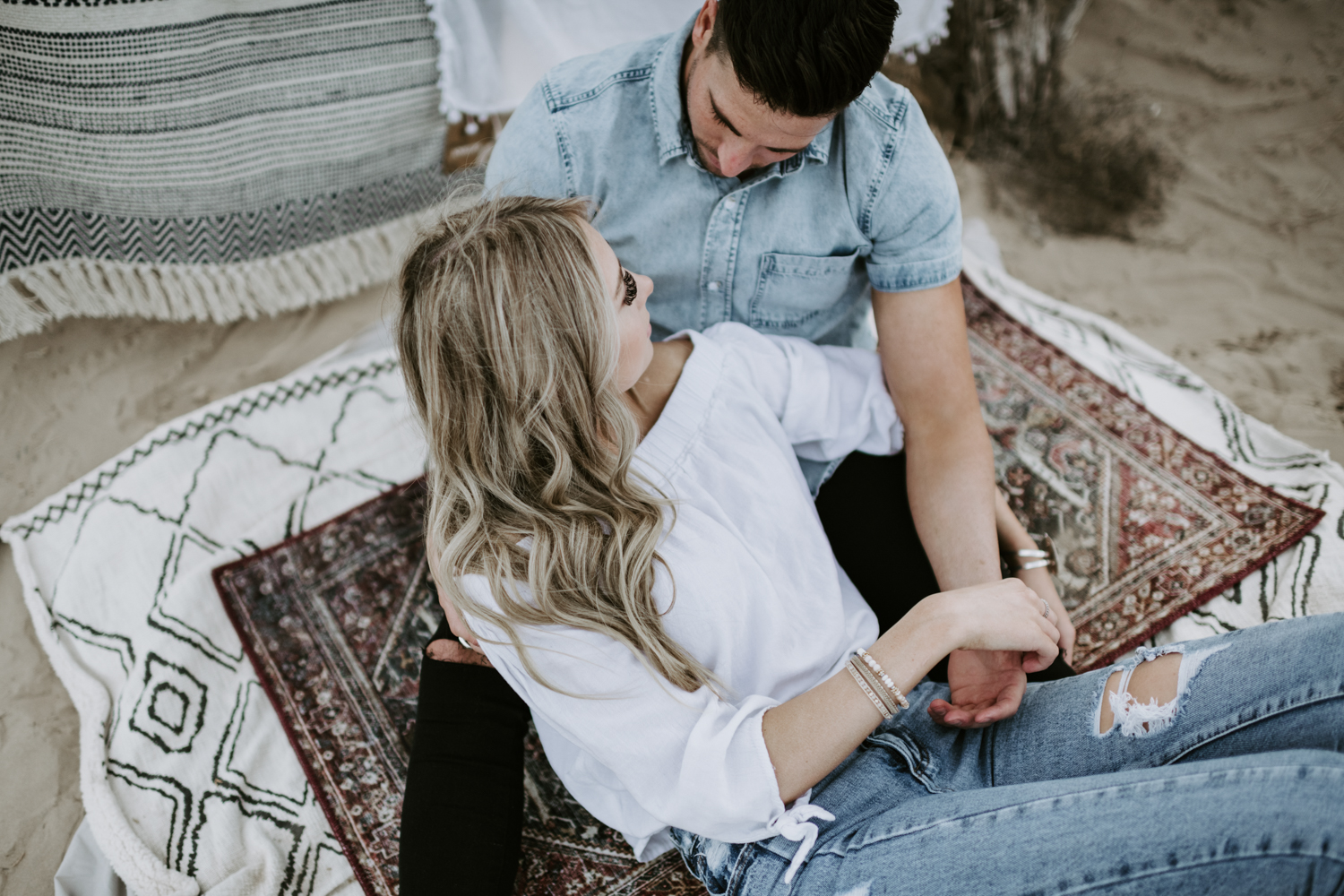 couple lying in the sand on rugs at utah sand dunes