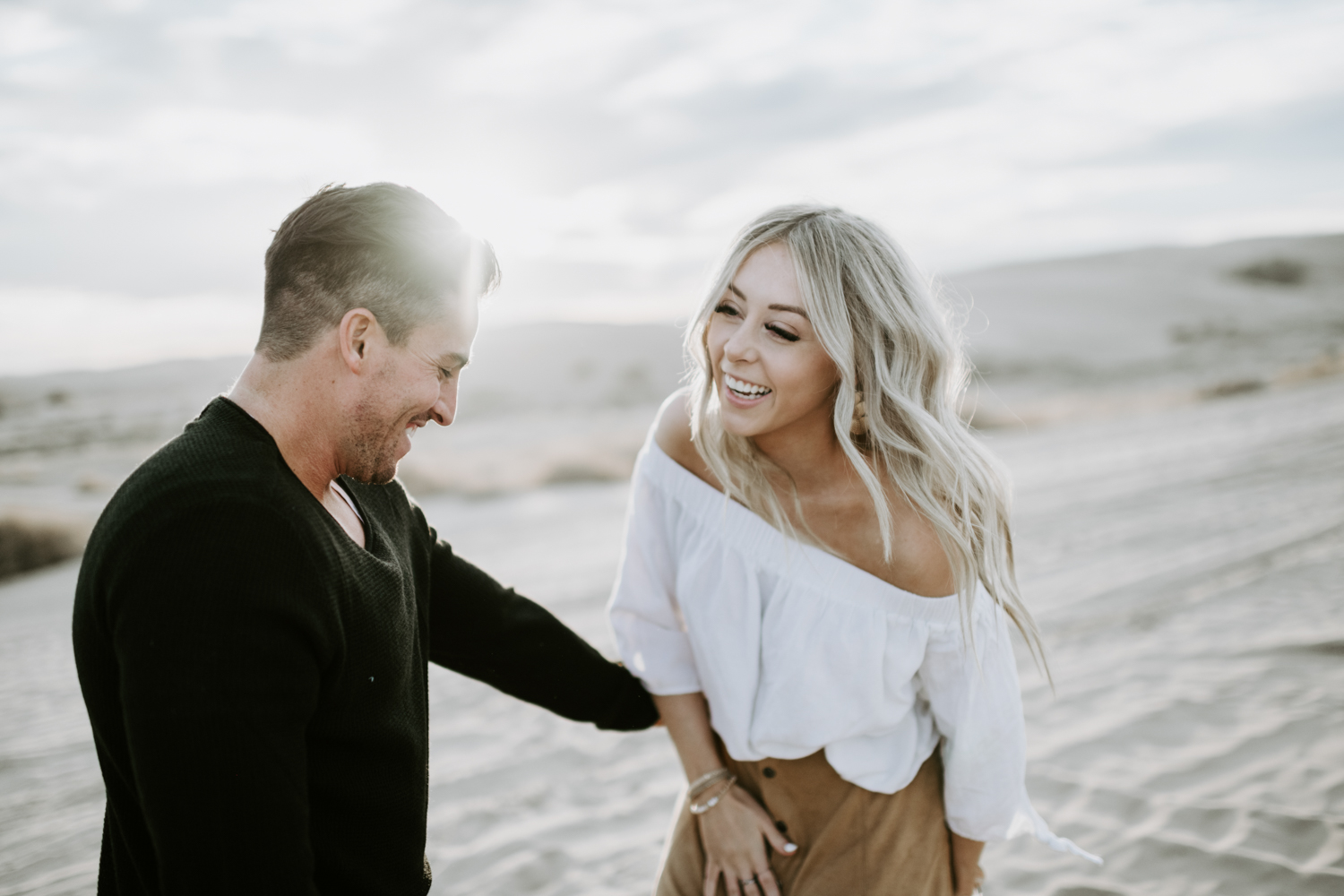 couple laughing holding hands at sand dunes in utah