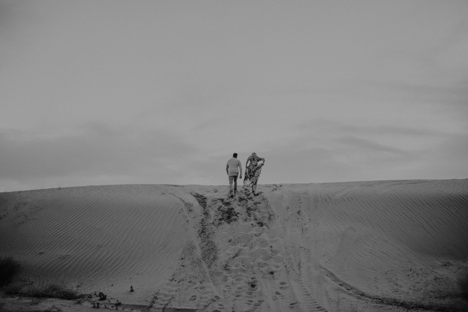 couple walking to top of sand dunes in utah
