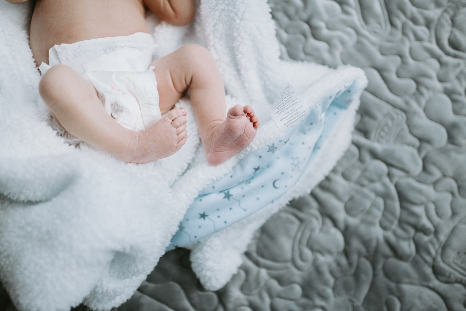 newborn baby boy in diaper lying on blanket on nursery floor