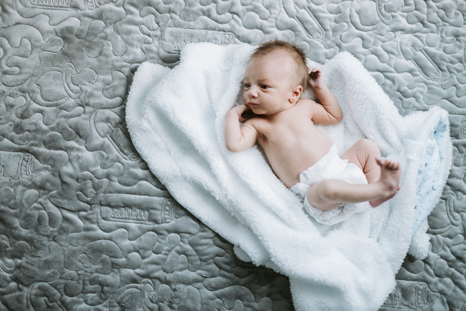 newborn baby boy lying on blanket on floor in nursery 
