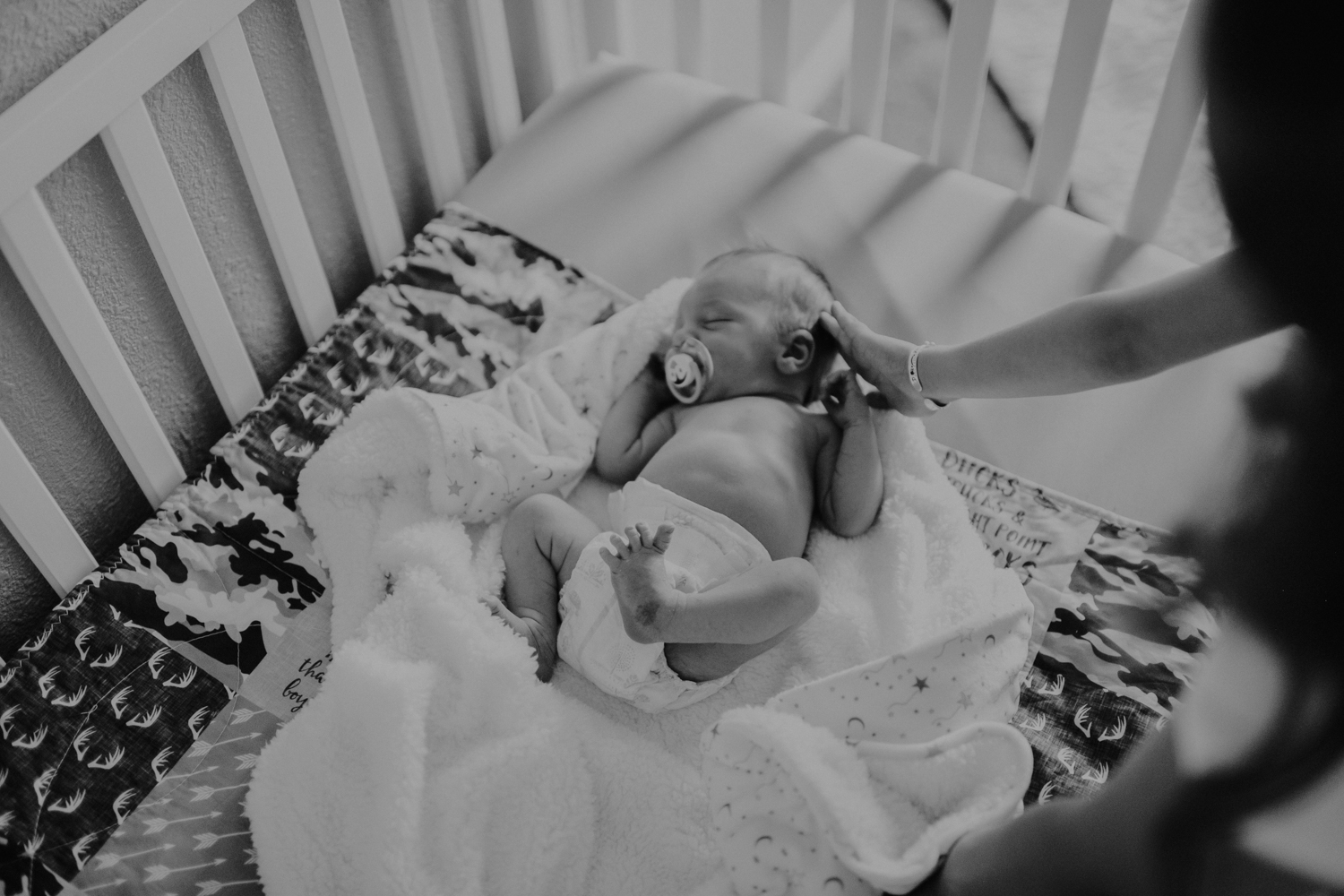 newborn baby boy lying in crib black and white