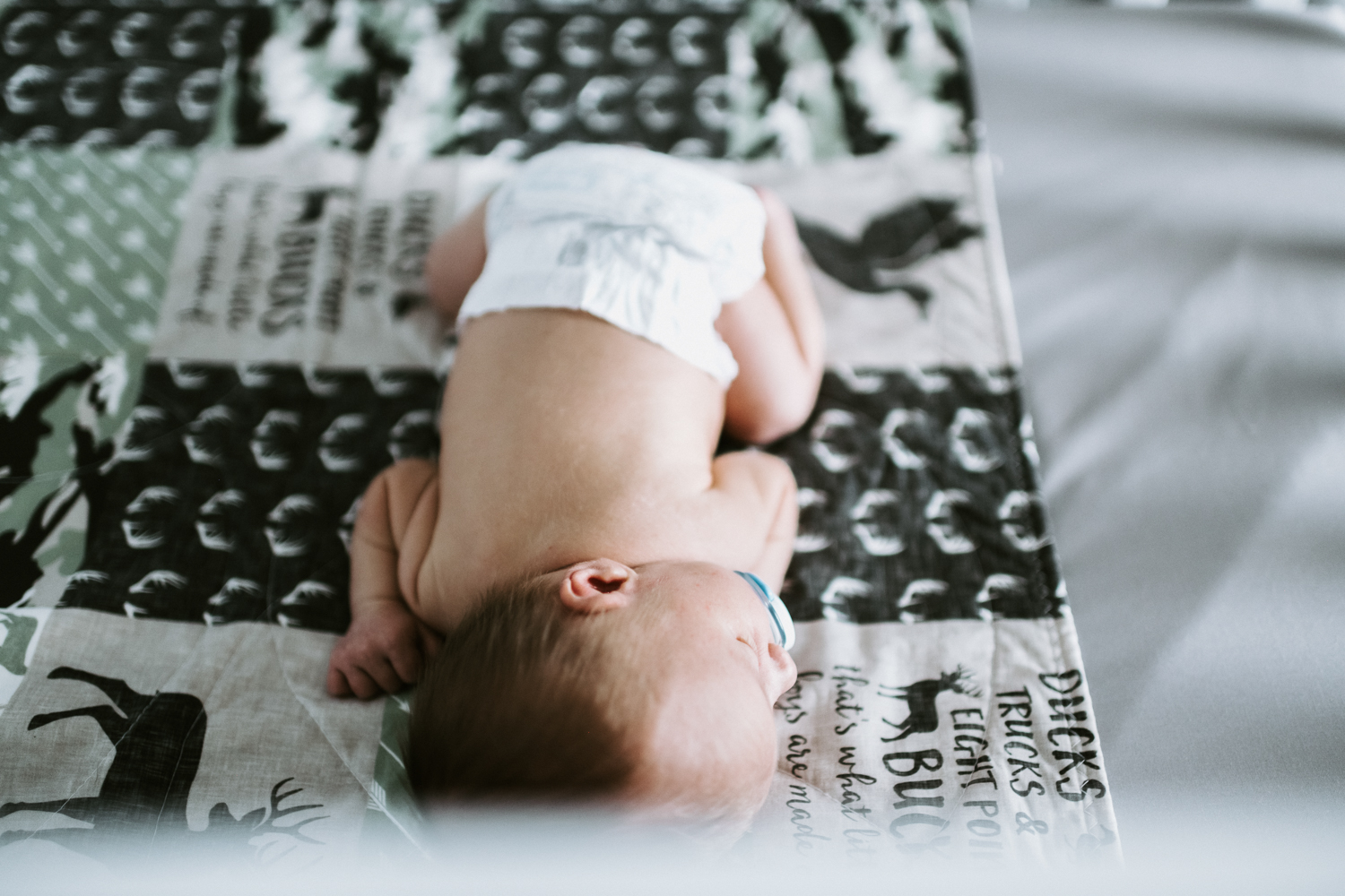 newborn baby boy lying in crib with checkered blanket