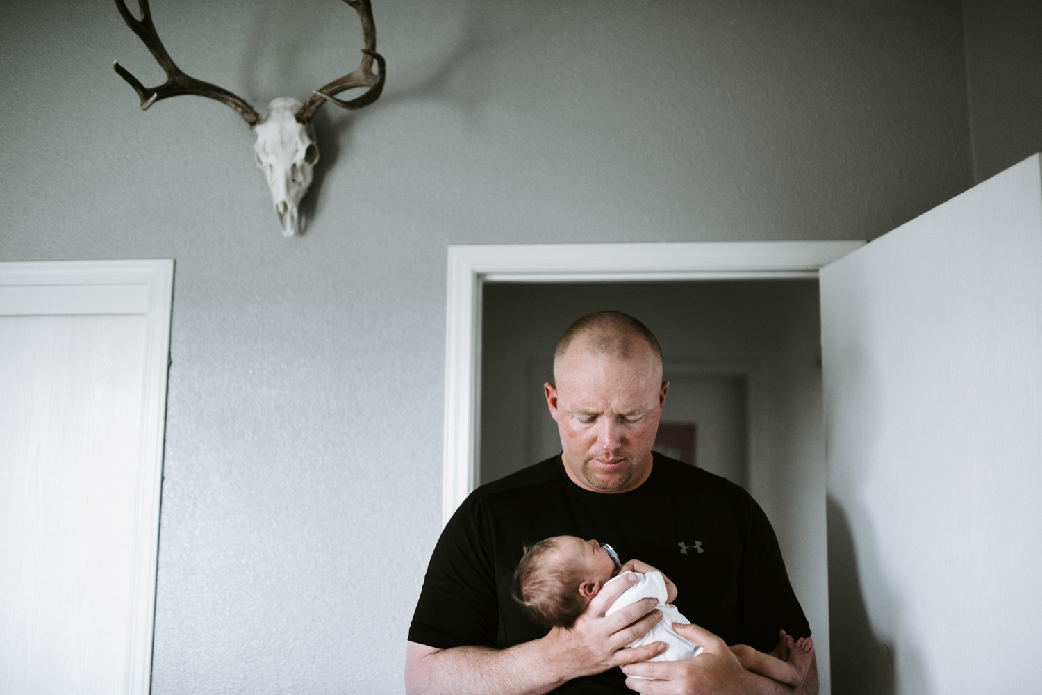 dad holding newborn baby boy in nursery with antlers on wall