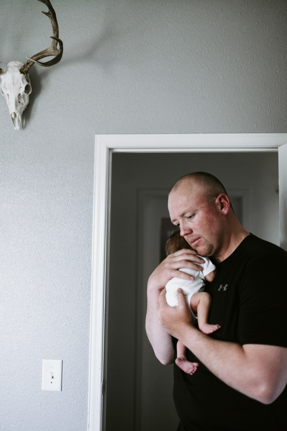 dad holding newborn baby boy in nursery with antlers on wall