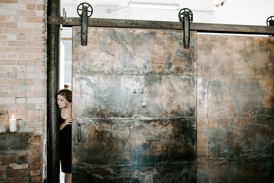 girl looking through industrial sliding door at wedding