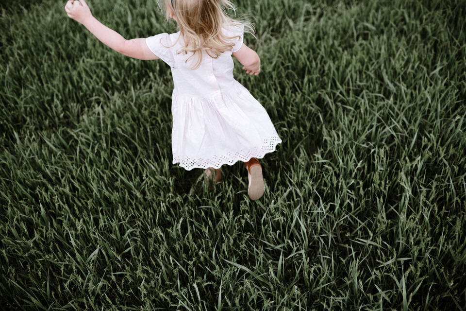 little girl in pink dress running through grass