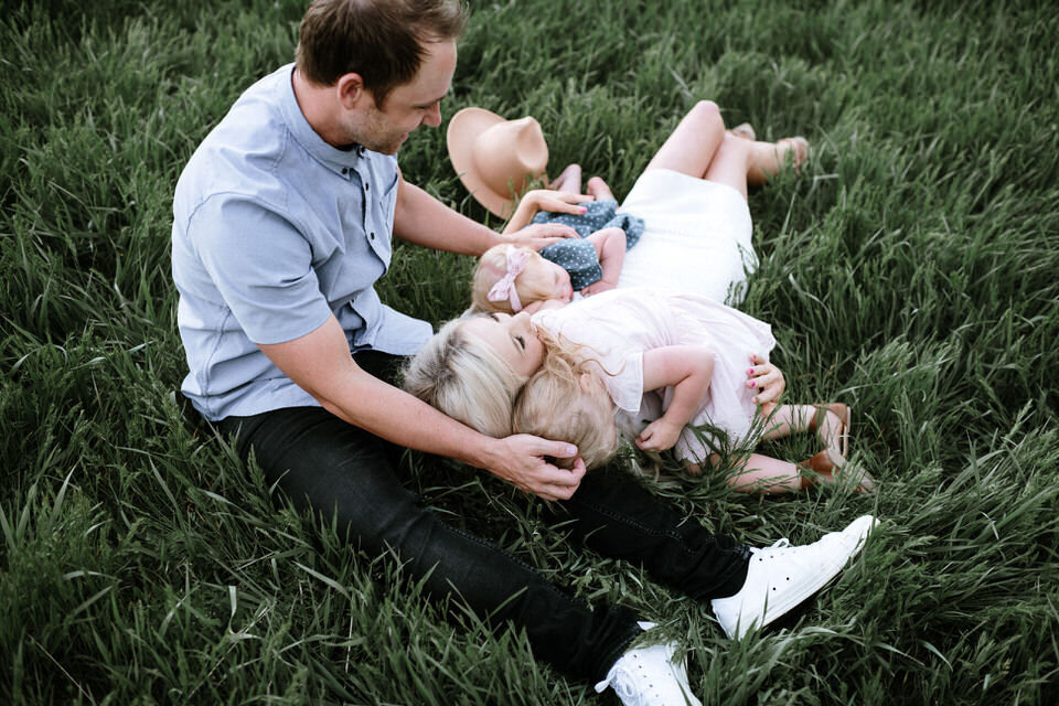 family of four lying on grass in each other's laps
