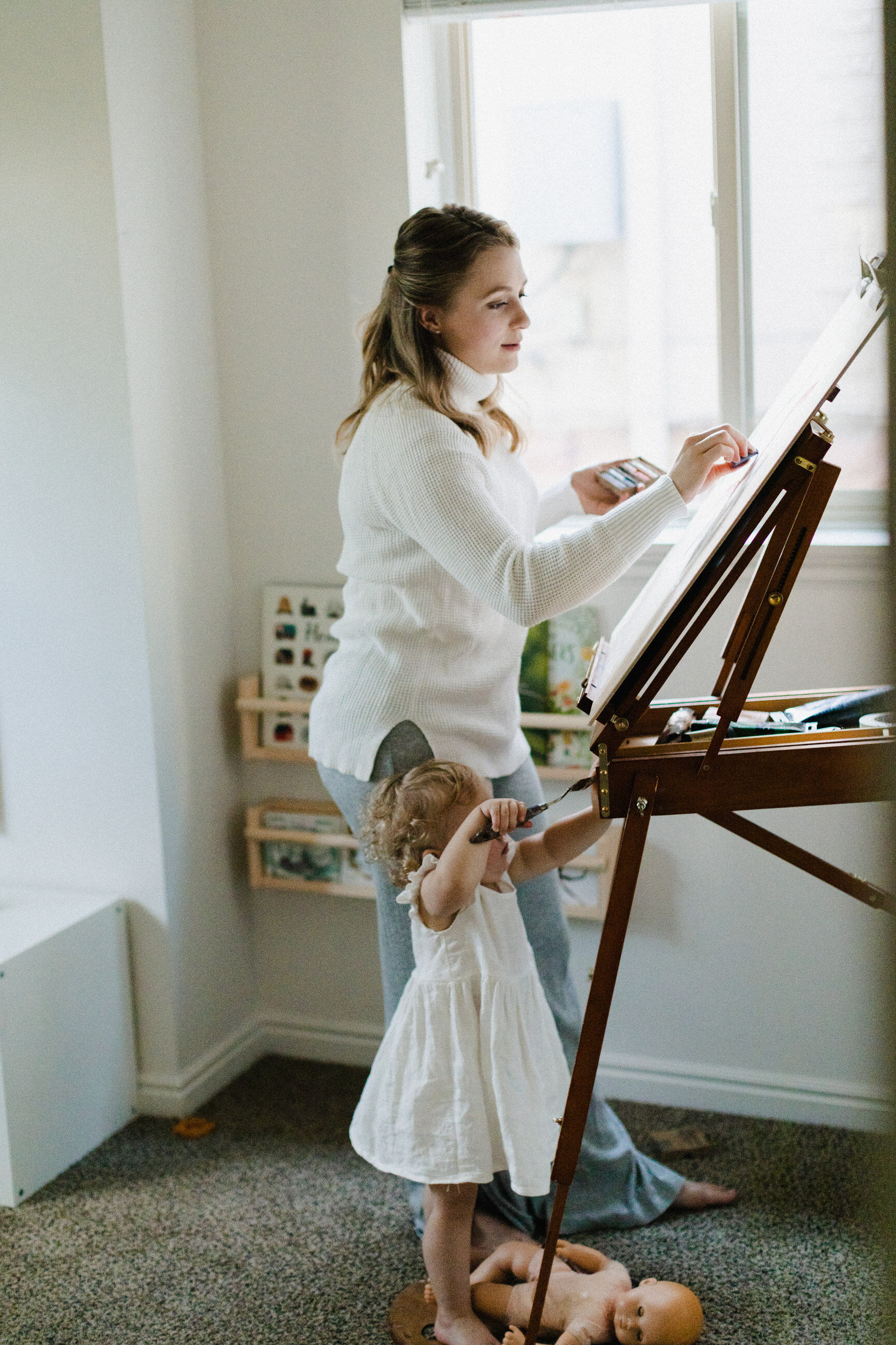 mom painting at easel while daughter watches
