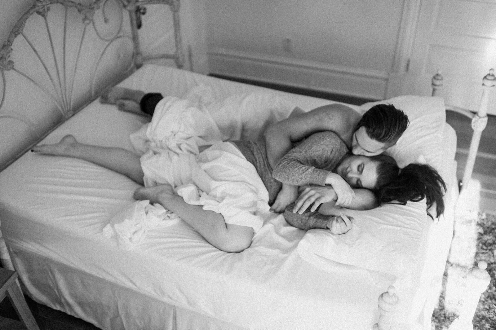 couple snuggling in bed with white sheets 