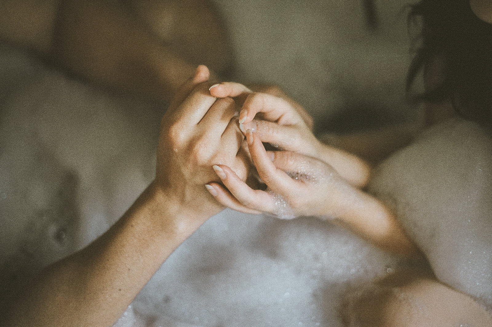 couple holding hands in bubble bath together