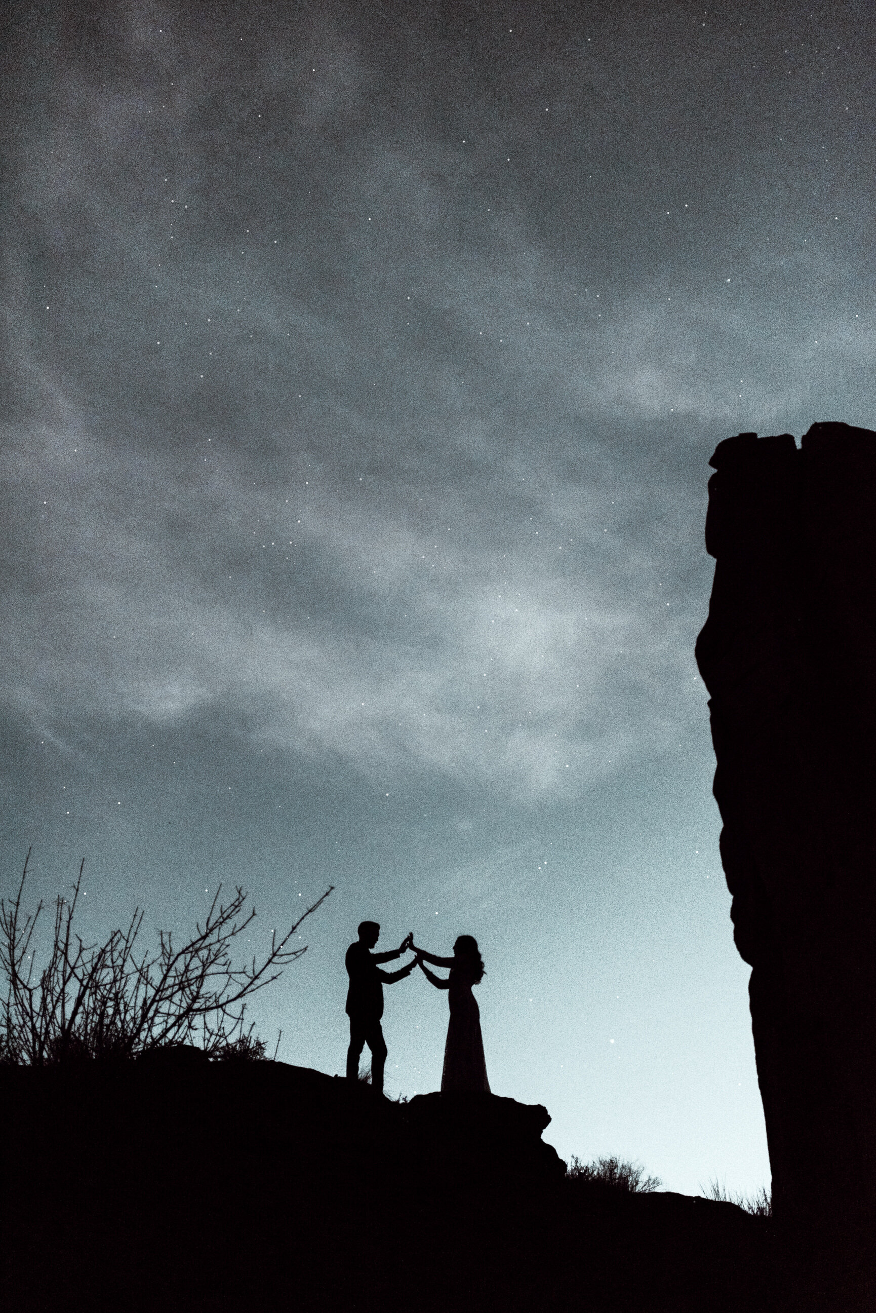 couple dancing under dark starry sky on top of cliffs