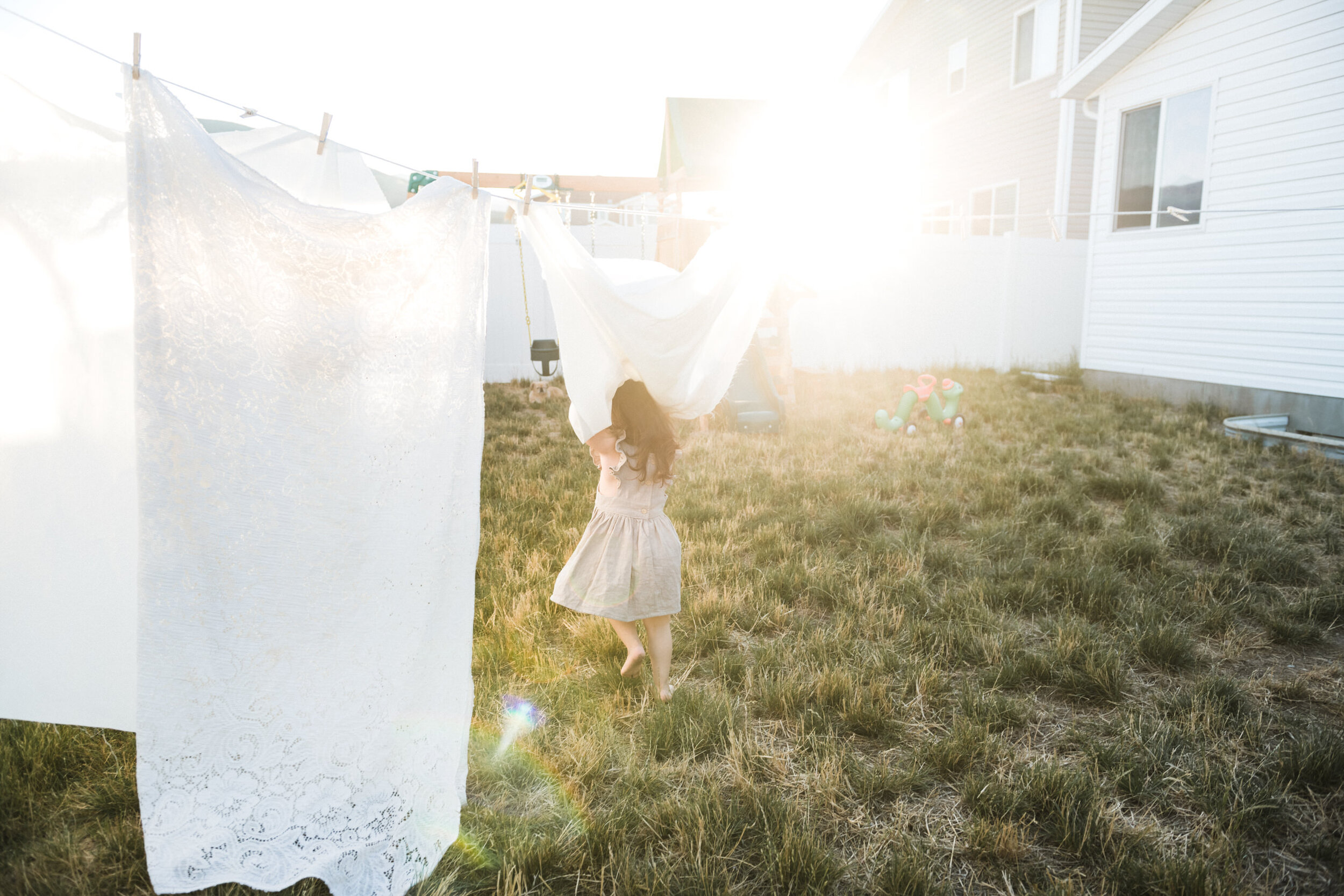 little girl running through sheets in backyard