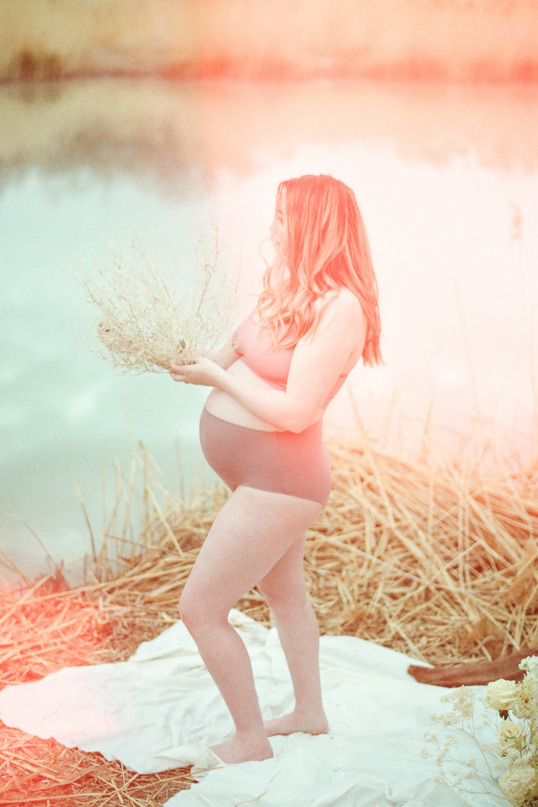 pregnant mom holding tumbleweed in front of river