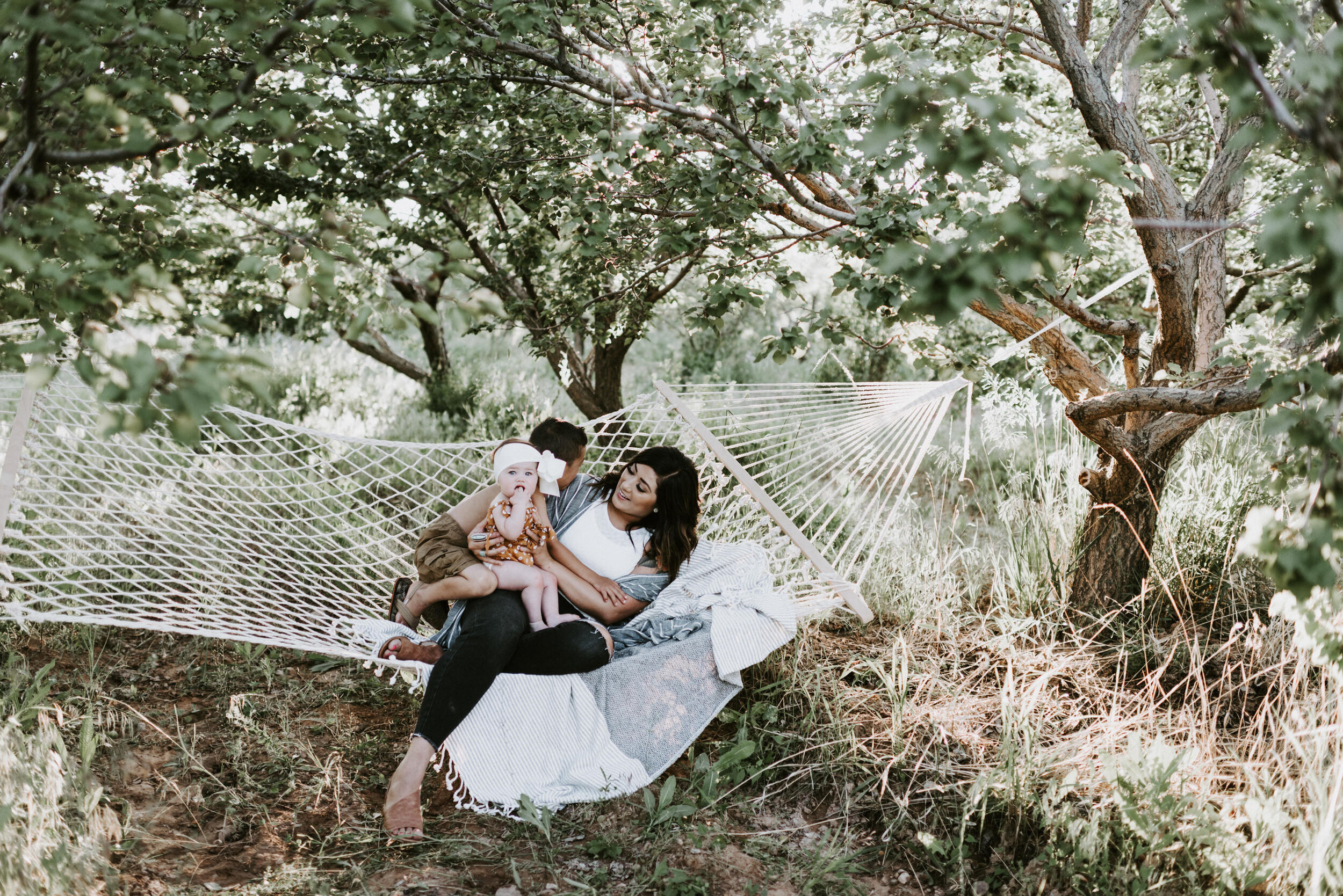 mom sitting in hammock with children in apple orchard
