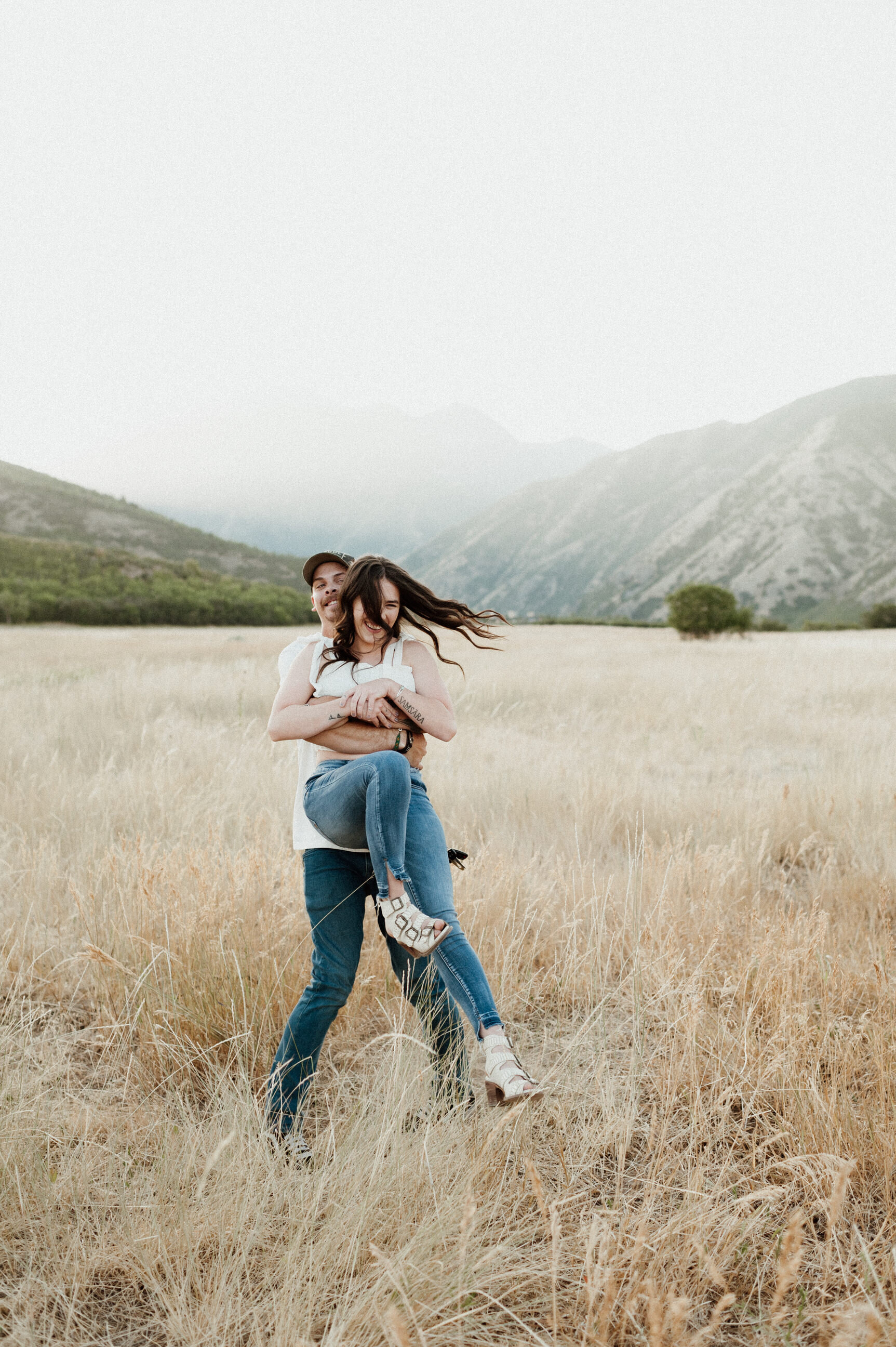 couple spinning around in golden field in the mountains