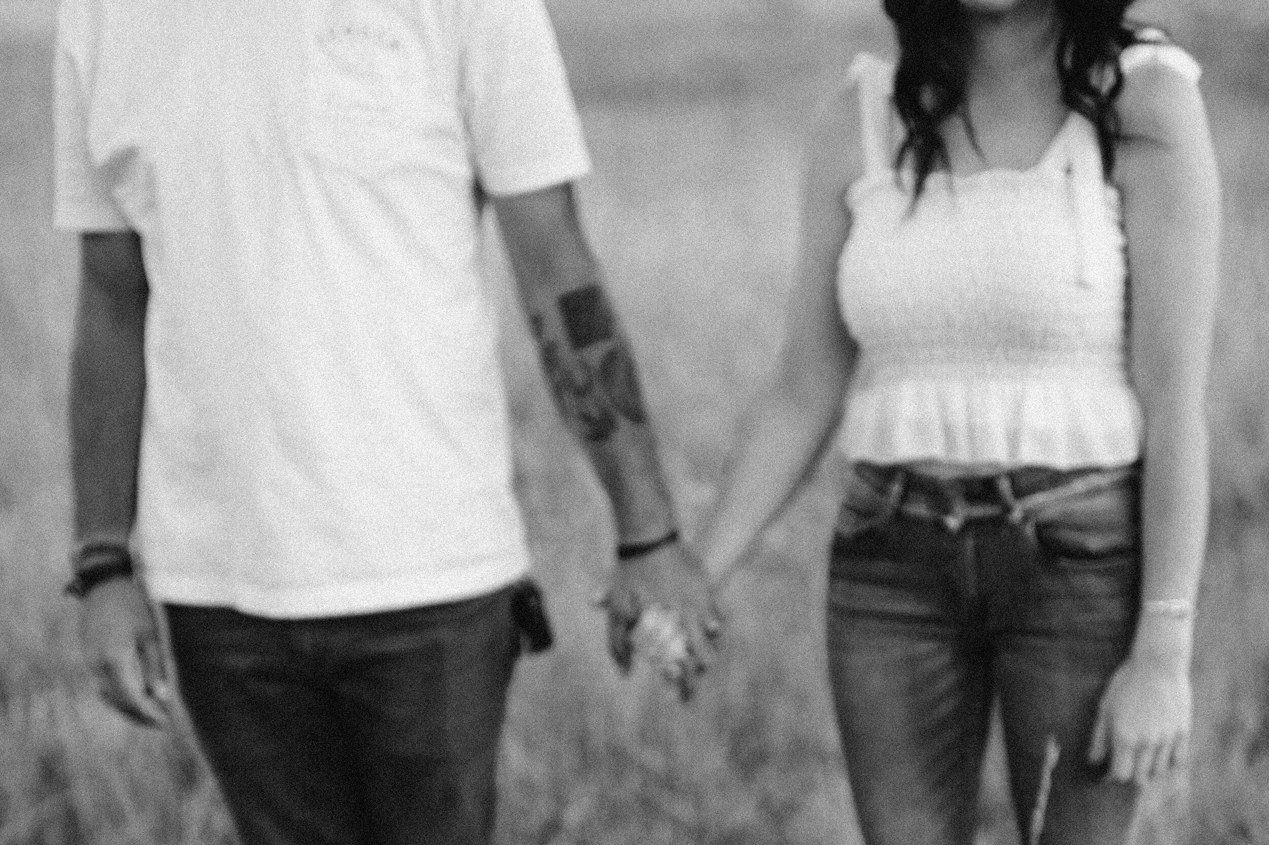 couple with tattoos in field holding hands