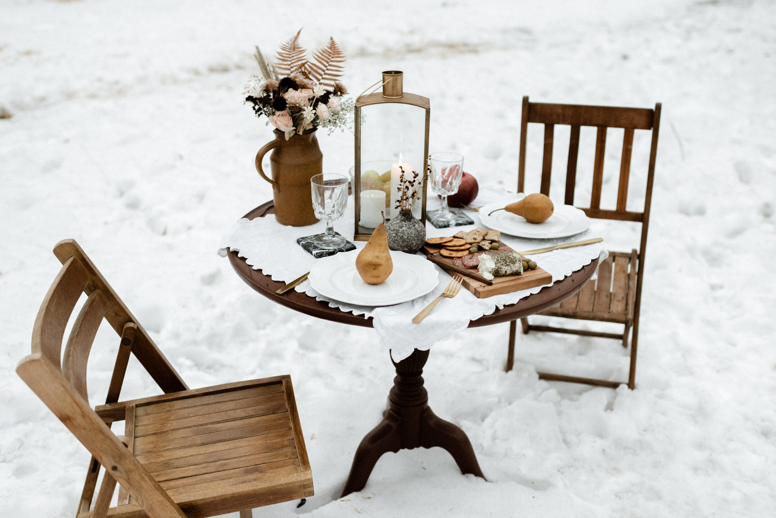 snowy picnic with wooden table with lantern charcuterie board 