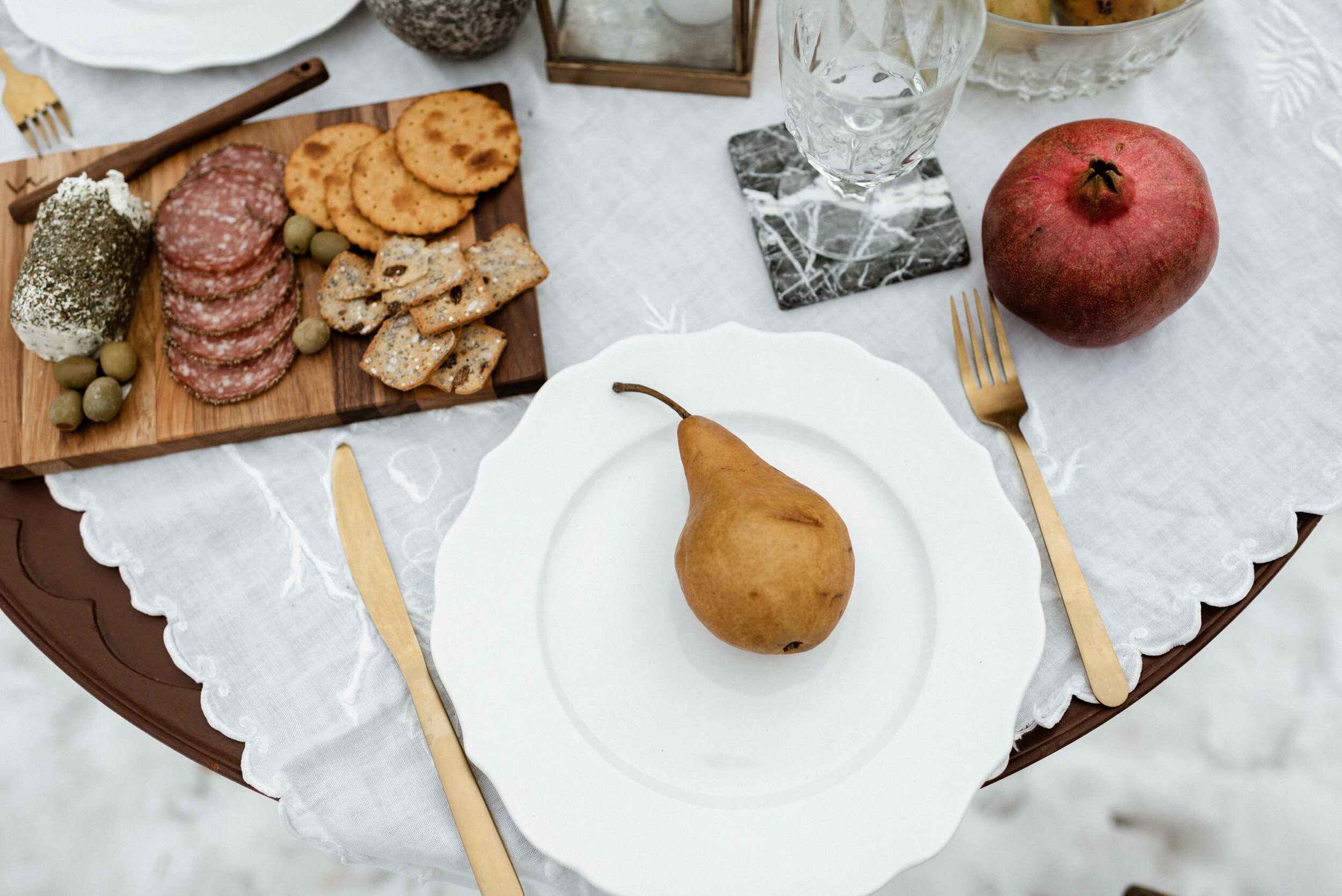 picnic table with pear, pomegranate, charcuterie board, gold cutlery
