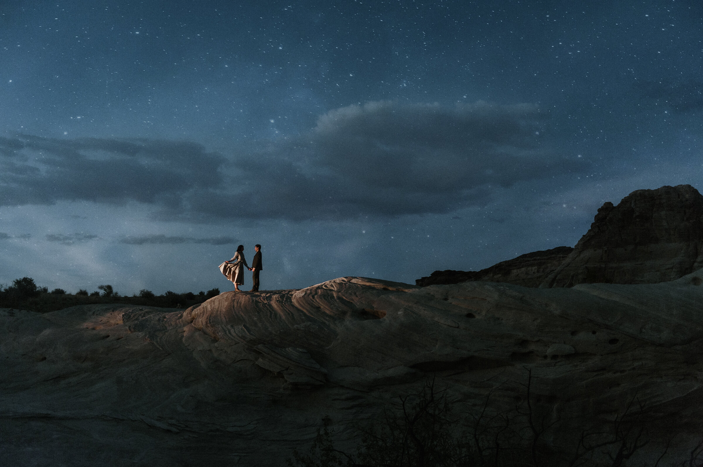 amangiri couple standing on top of rocks with stars in the night sky