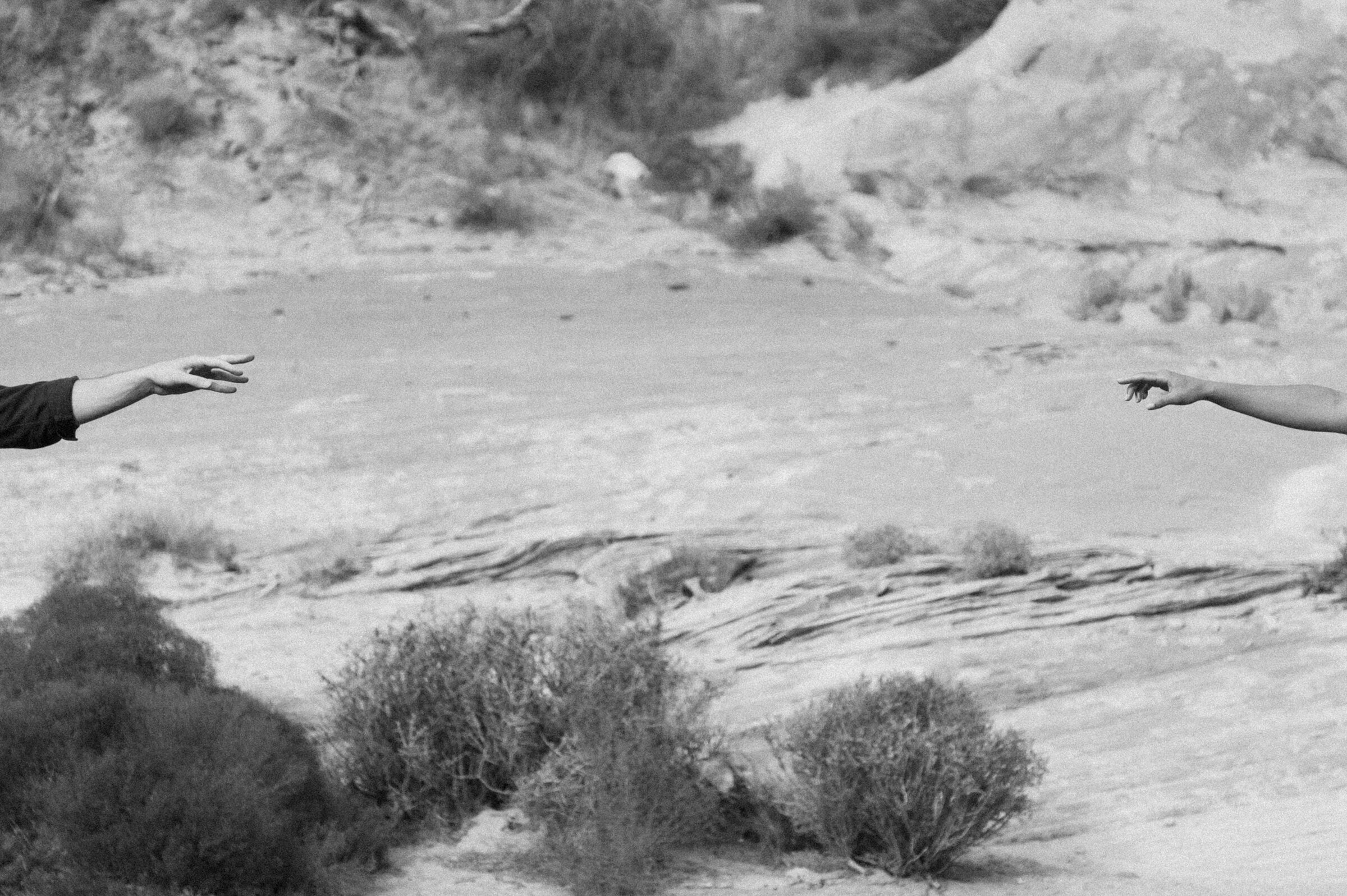 amangiri resort couple reaching hands towards each other rocks in background