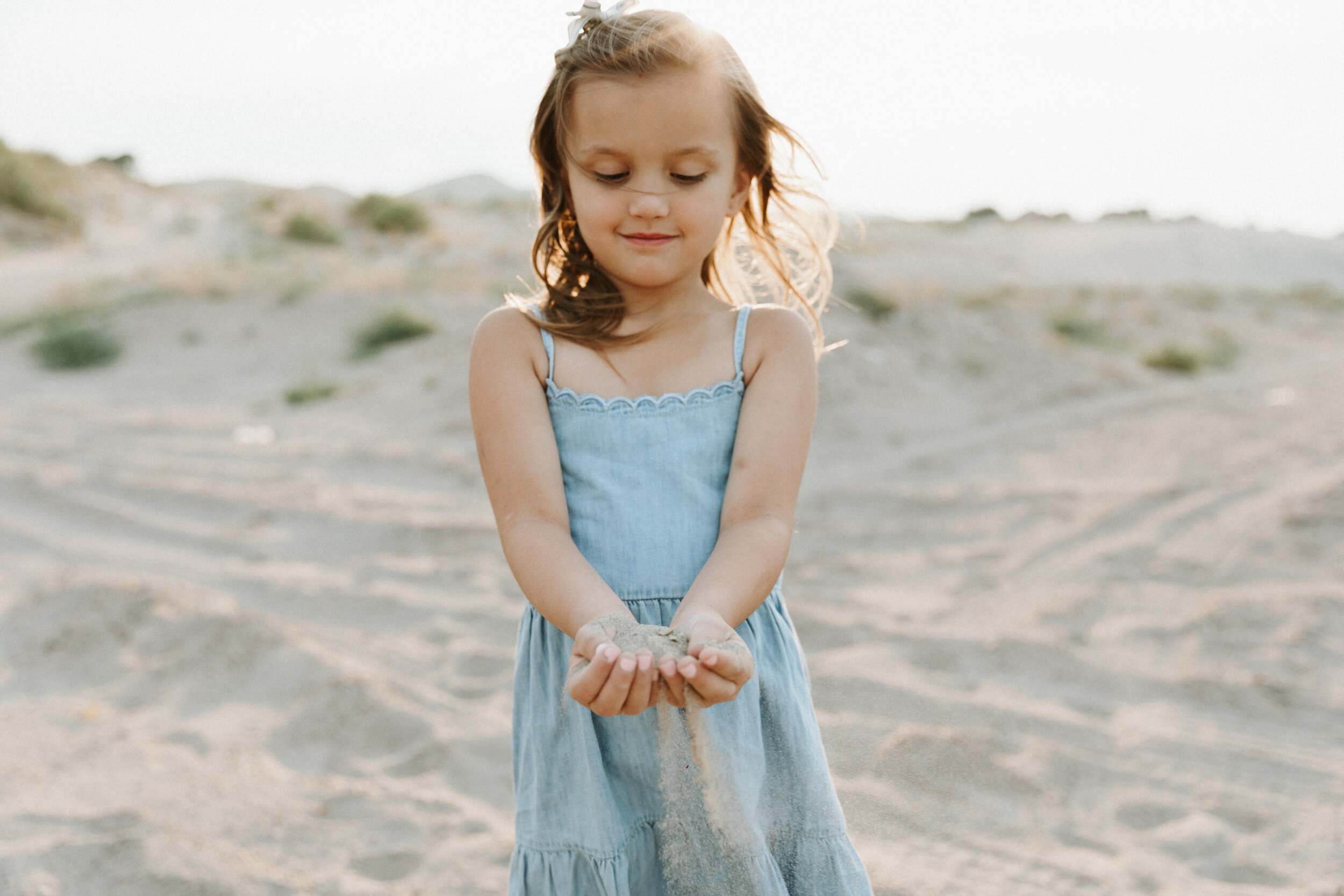 little girl letting sand fall through fingers