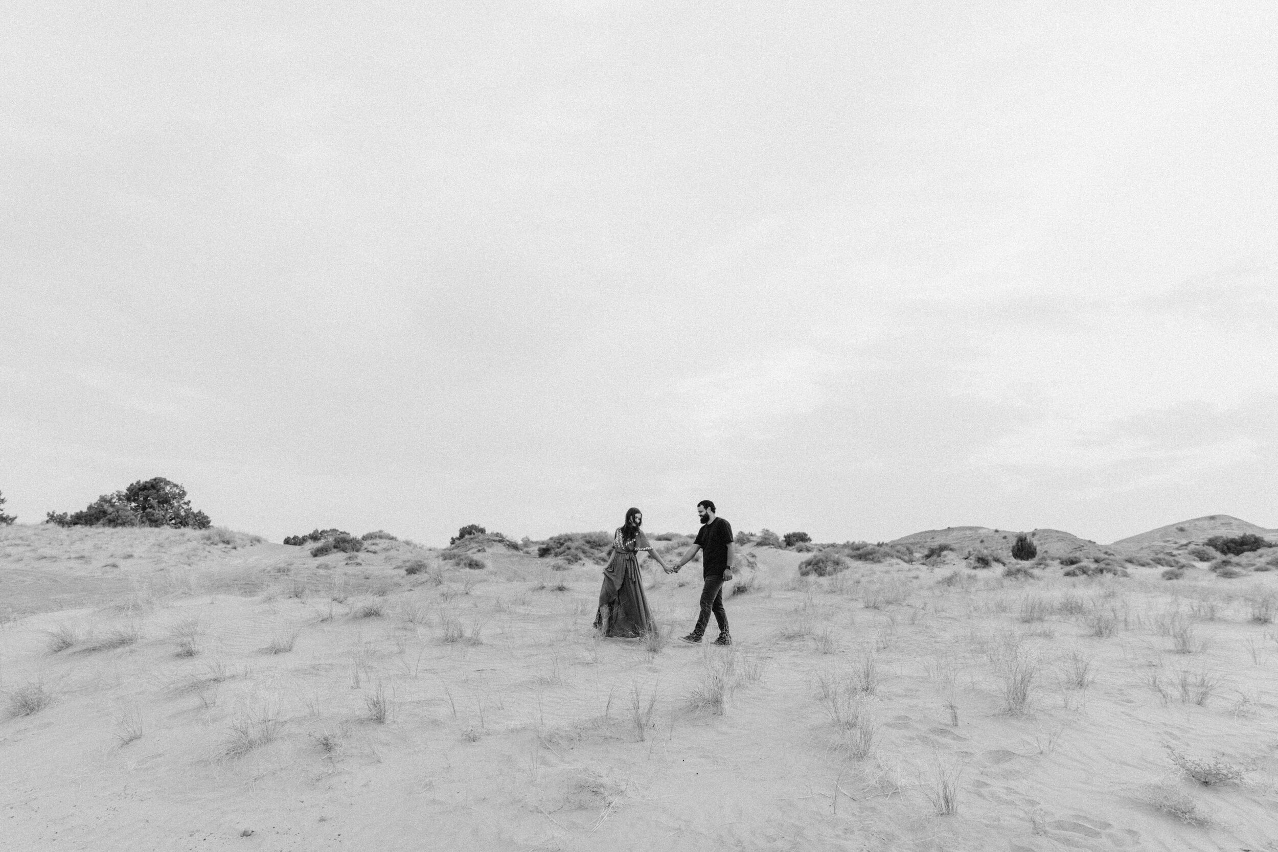 couple walking holding hands on sandy desert landscape