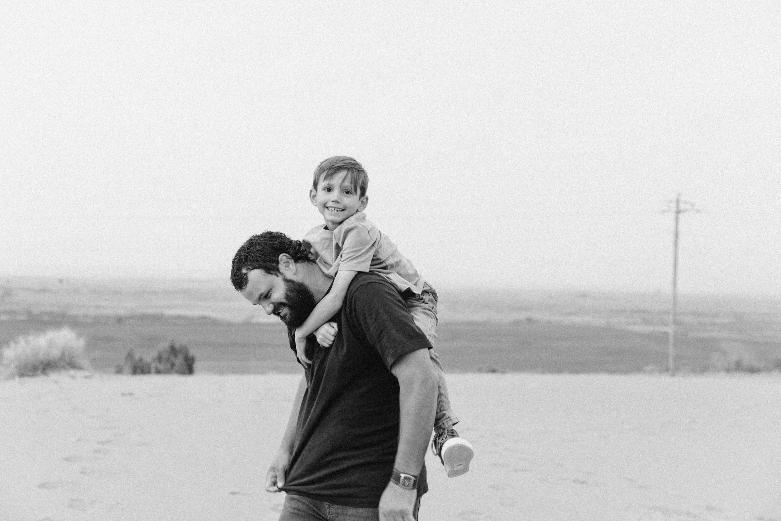 boy on dad's shoulders laughing