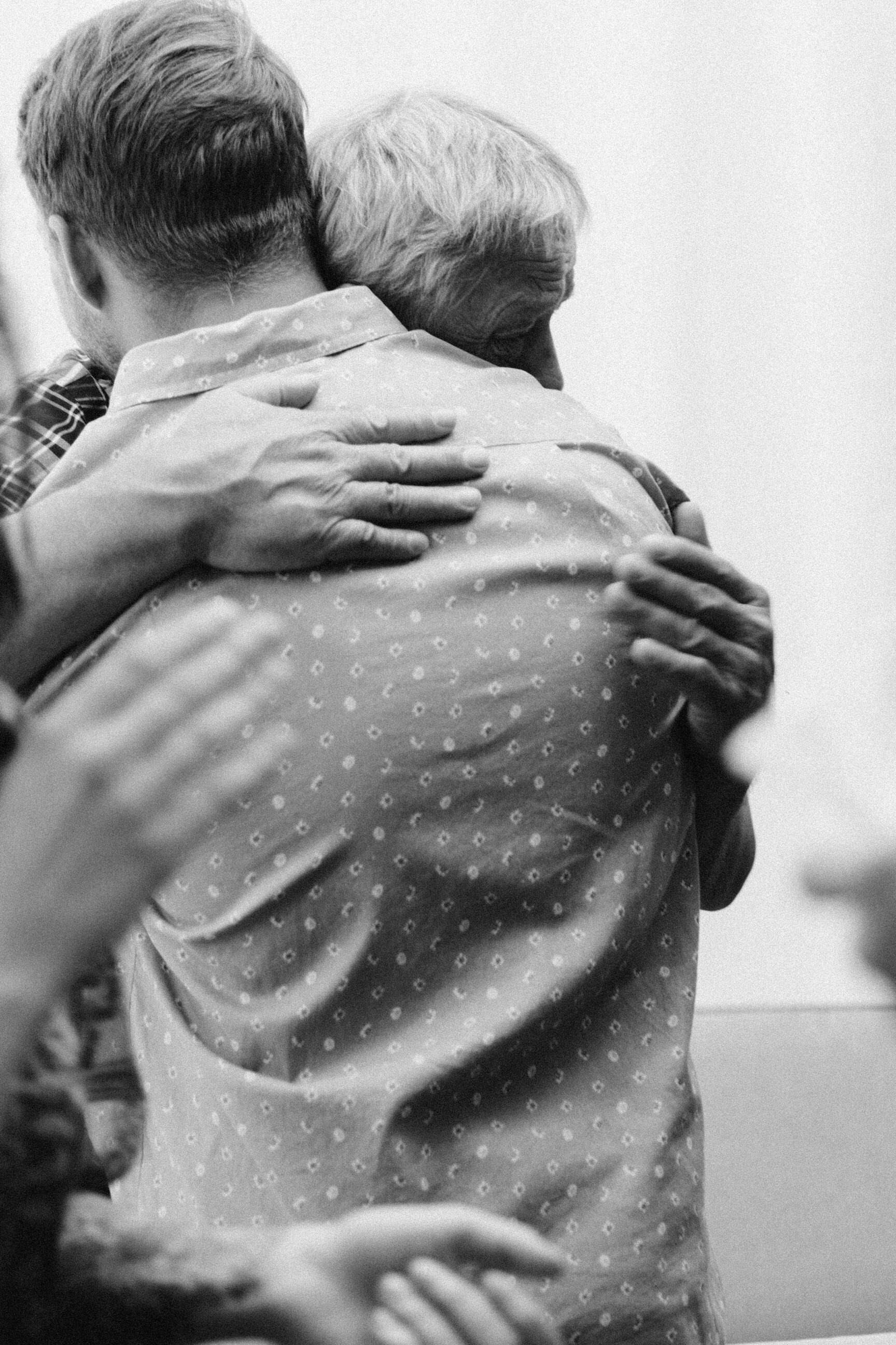 groom hugging dad at wedding black and white