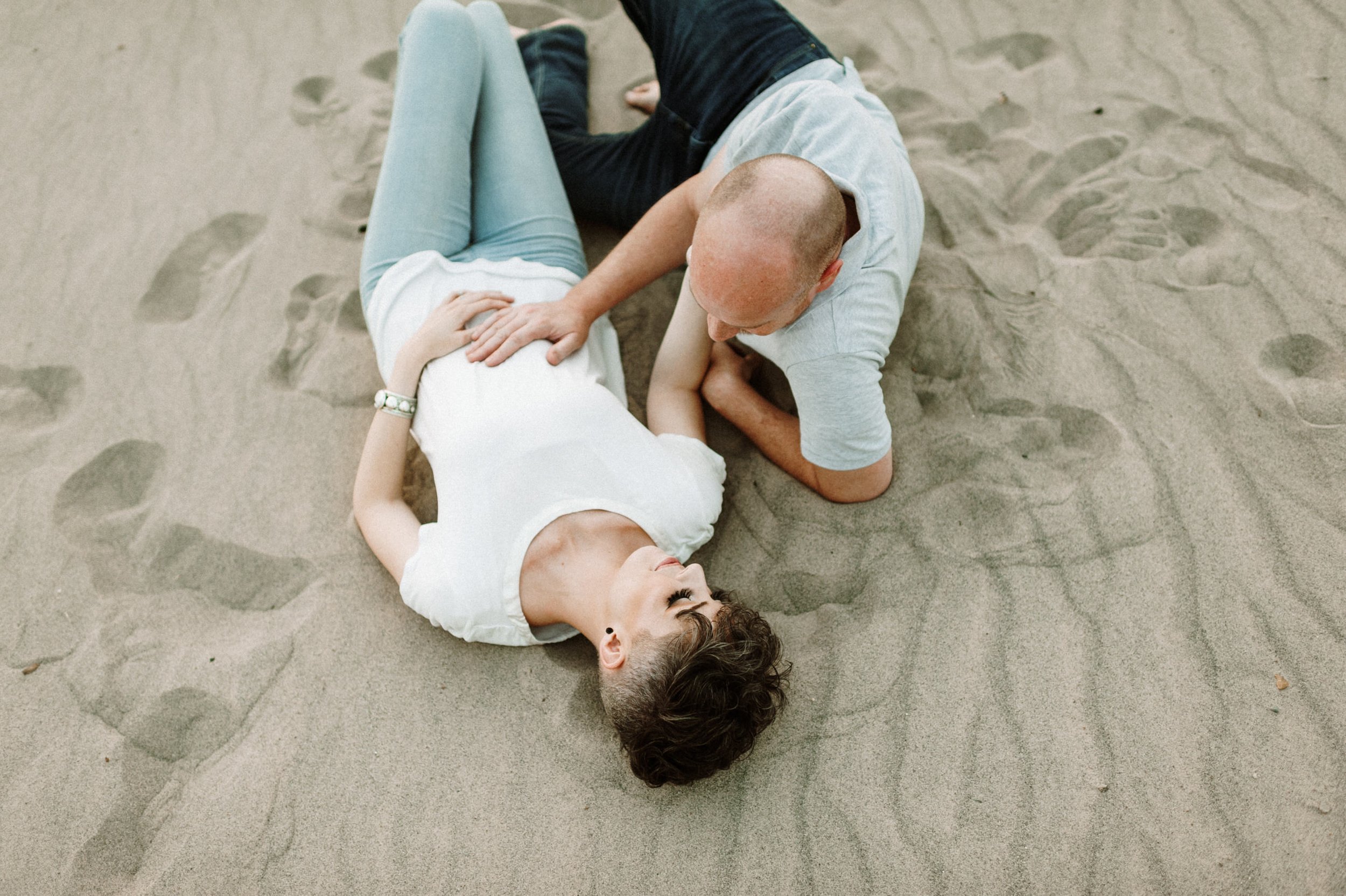 male female couple lying in sand together