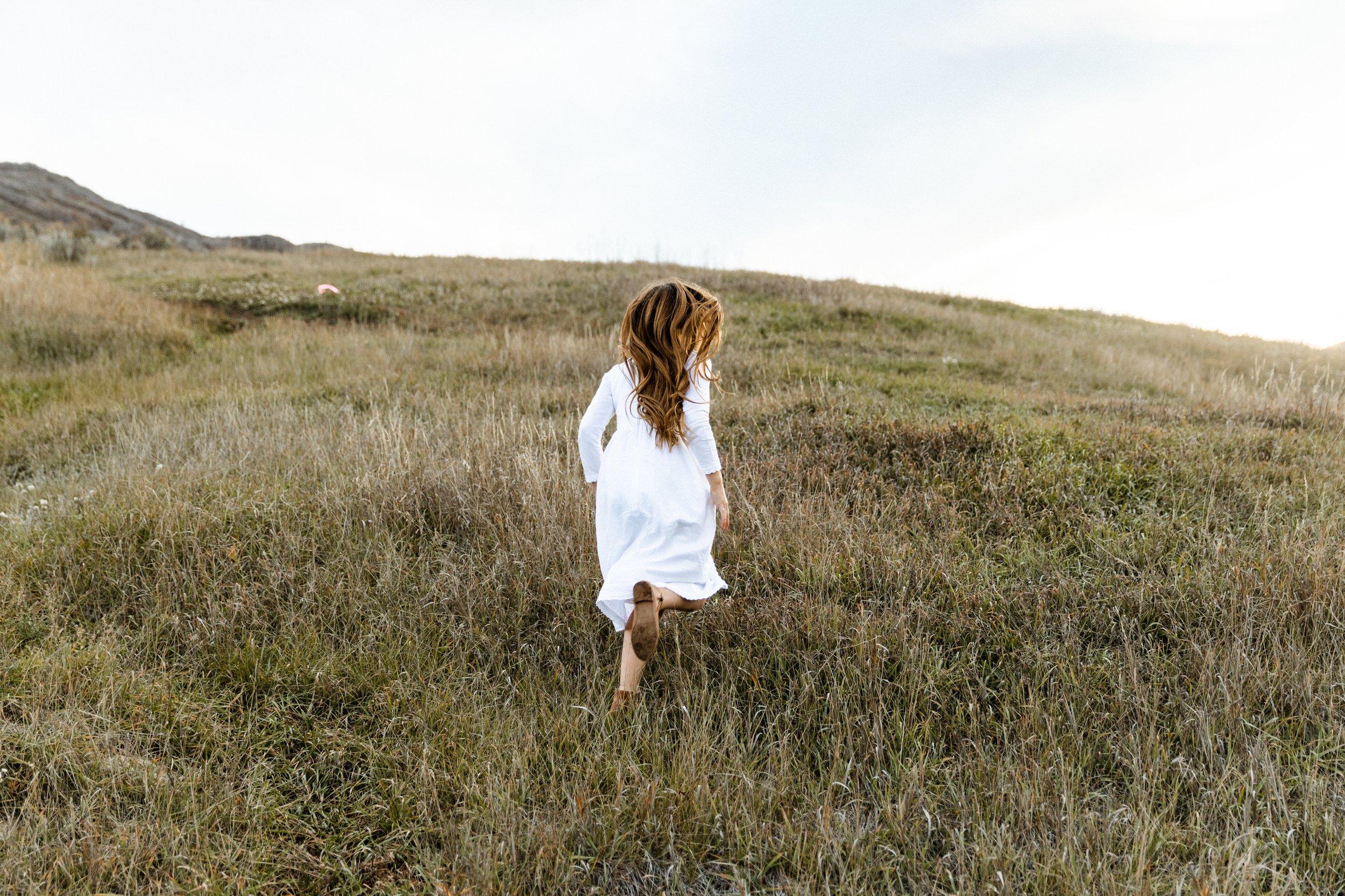girl white dressing running up grassy hill