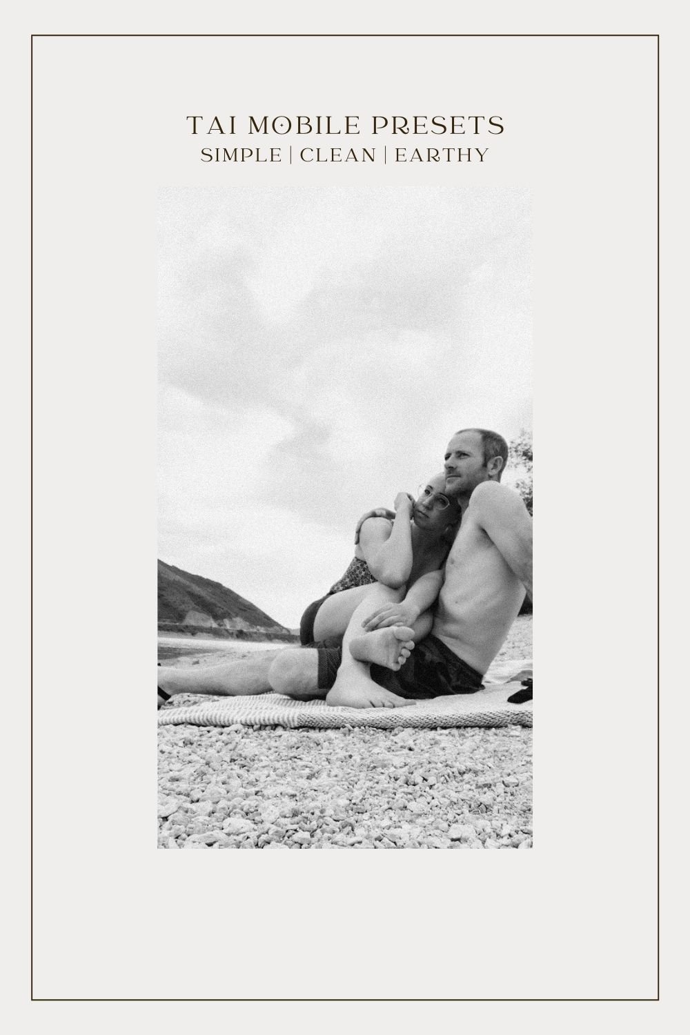 couple snuggling on rocky beach on blanket black and white