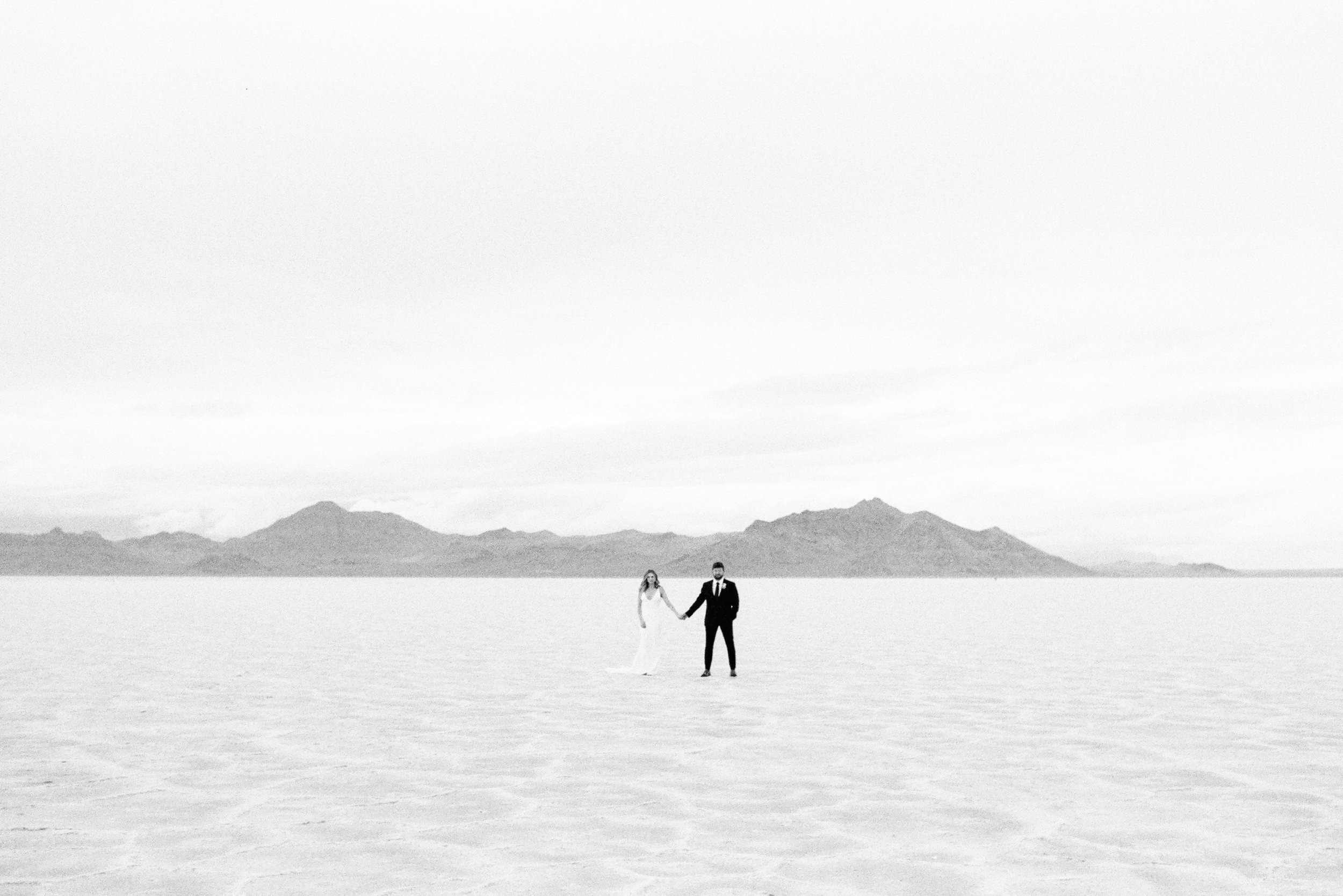 wedding couple holding hands on salt flats black and white