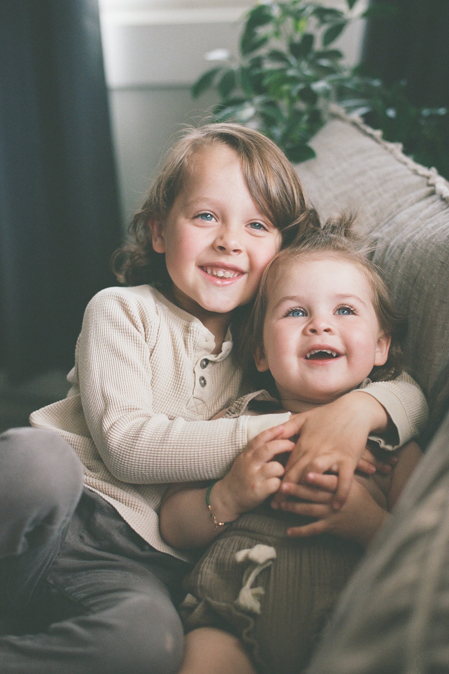 toddler boy and girl hugging laughing looking at camera neutral clothes