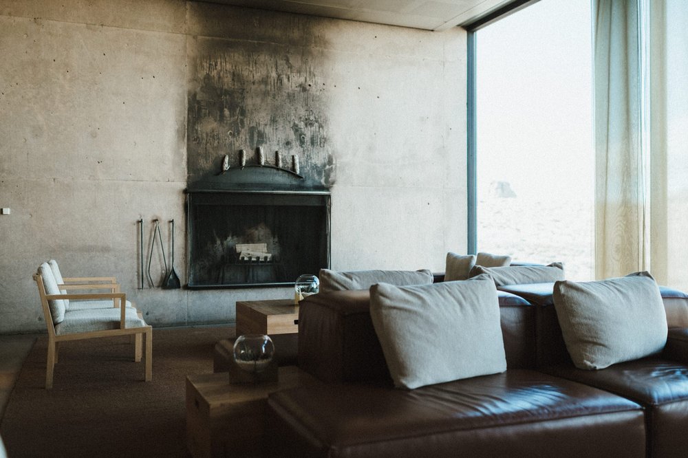 amangiri lobby couches fireplace concrete wall floor to ceiling glass windows