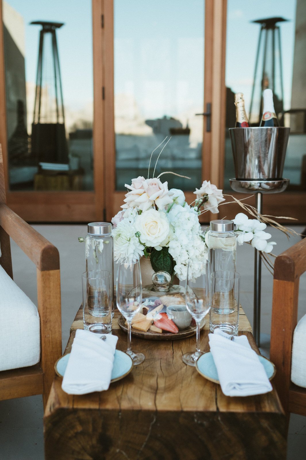 charcuterie board with flowers and wine glasses on wooden table at amangiri