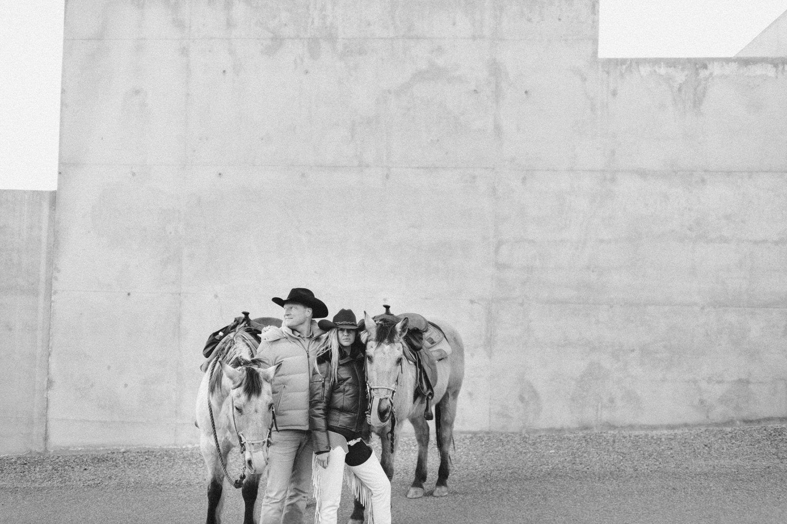 black and white film of couple standing next to horses at amangiri