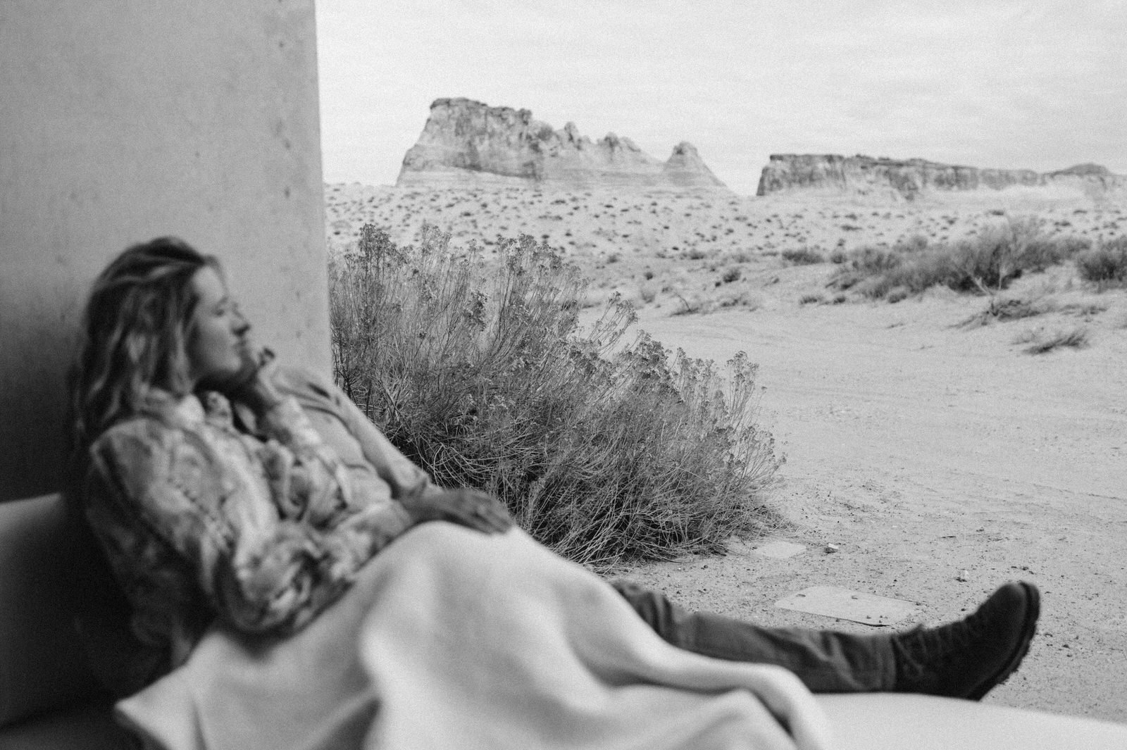 black and white photo couple blurry desert background in focus snuggling in white blanket on veranda amangiri