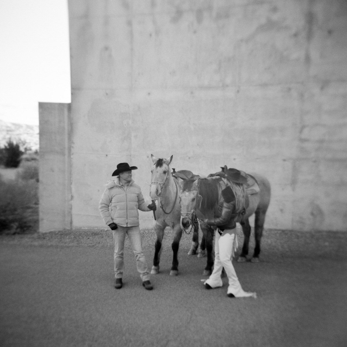 black and white film of couple standing next to horses at amangiri