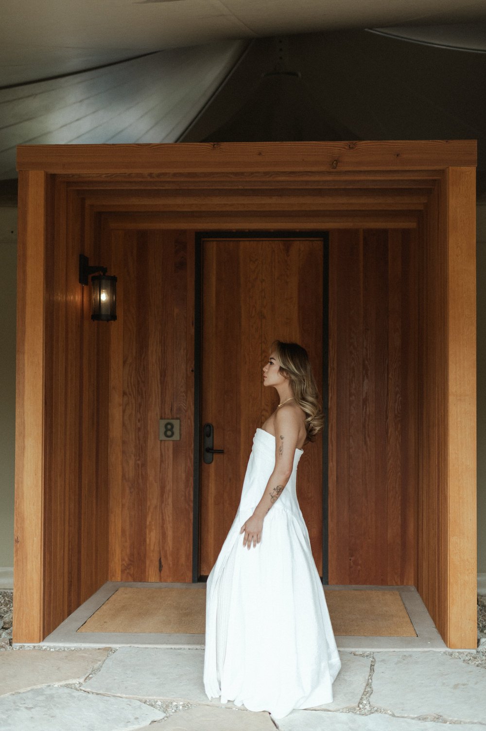 woman of color in white dress in front of wooden doors at amangiri camp sarika