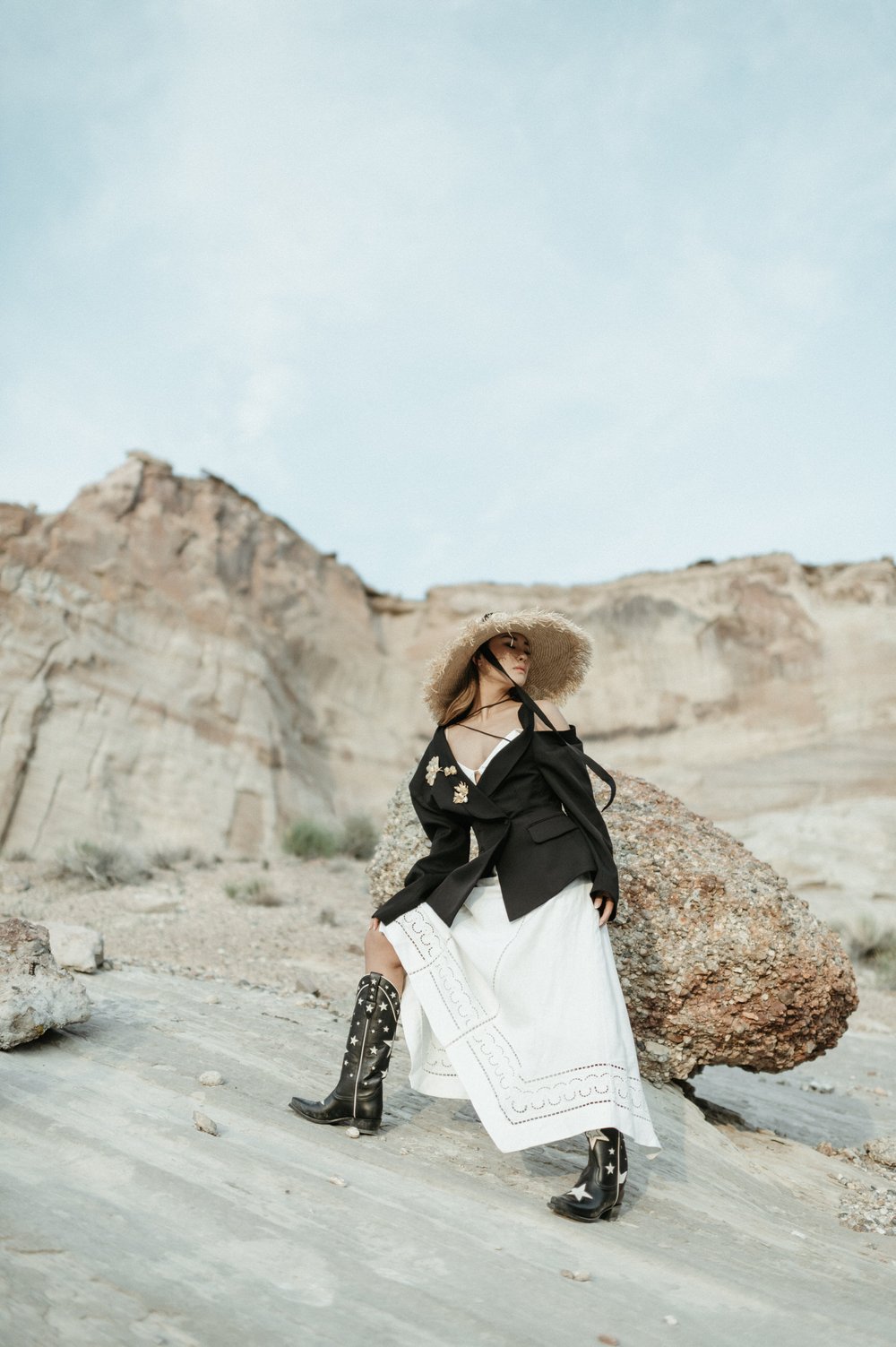 black and white photo of woman in asymmetrical dress with oversized black blazer with desert mesa backdrop 