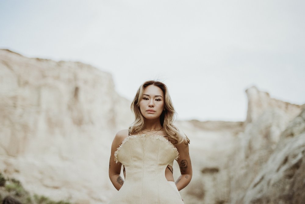 asian woman of color in editorial straw top with desert mesa background looking at camera