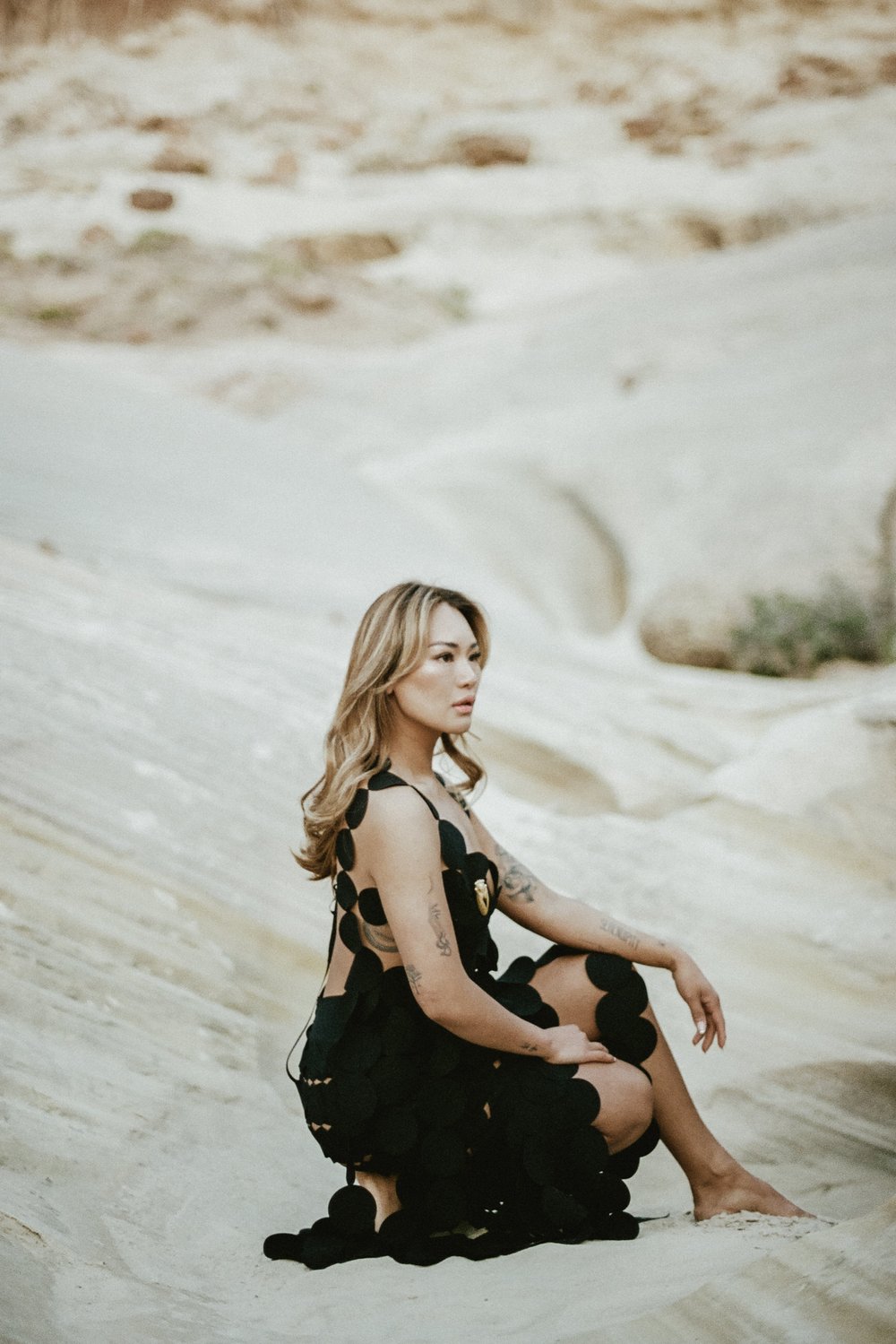 woman in desert kneeling down on rock black circle cutout dress