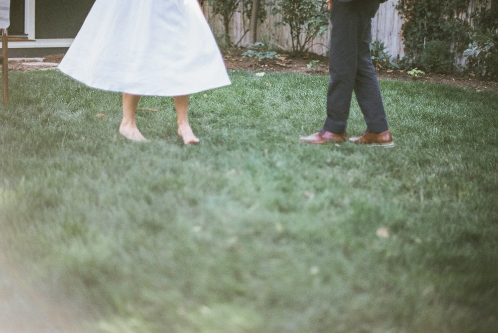 color film photo of bride and groom waist down dancing in green grass