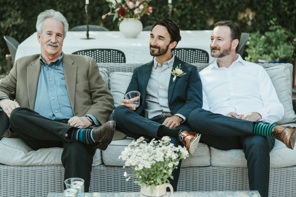 dad and two sons in suits with their foot resting up on leg