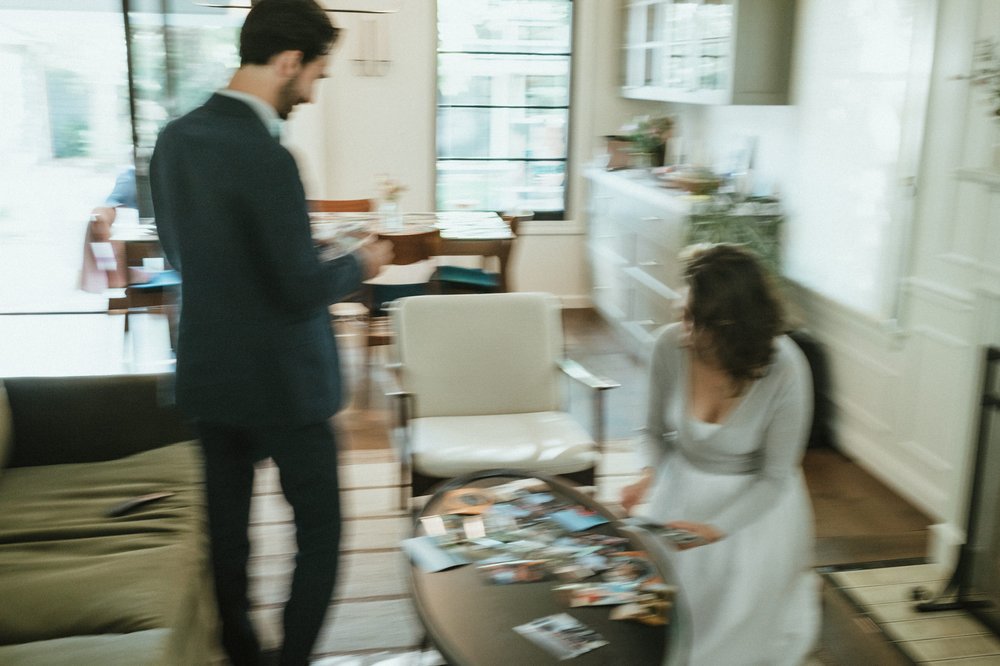 blurry color photo bride and groom in their home with 4x6 photos on dining table