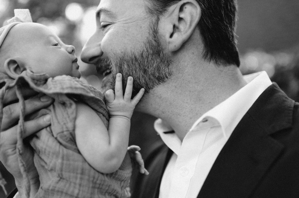 dad with newborn daughter her hand on his beard