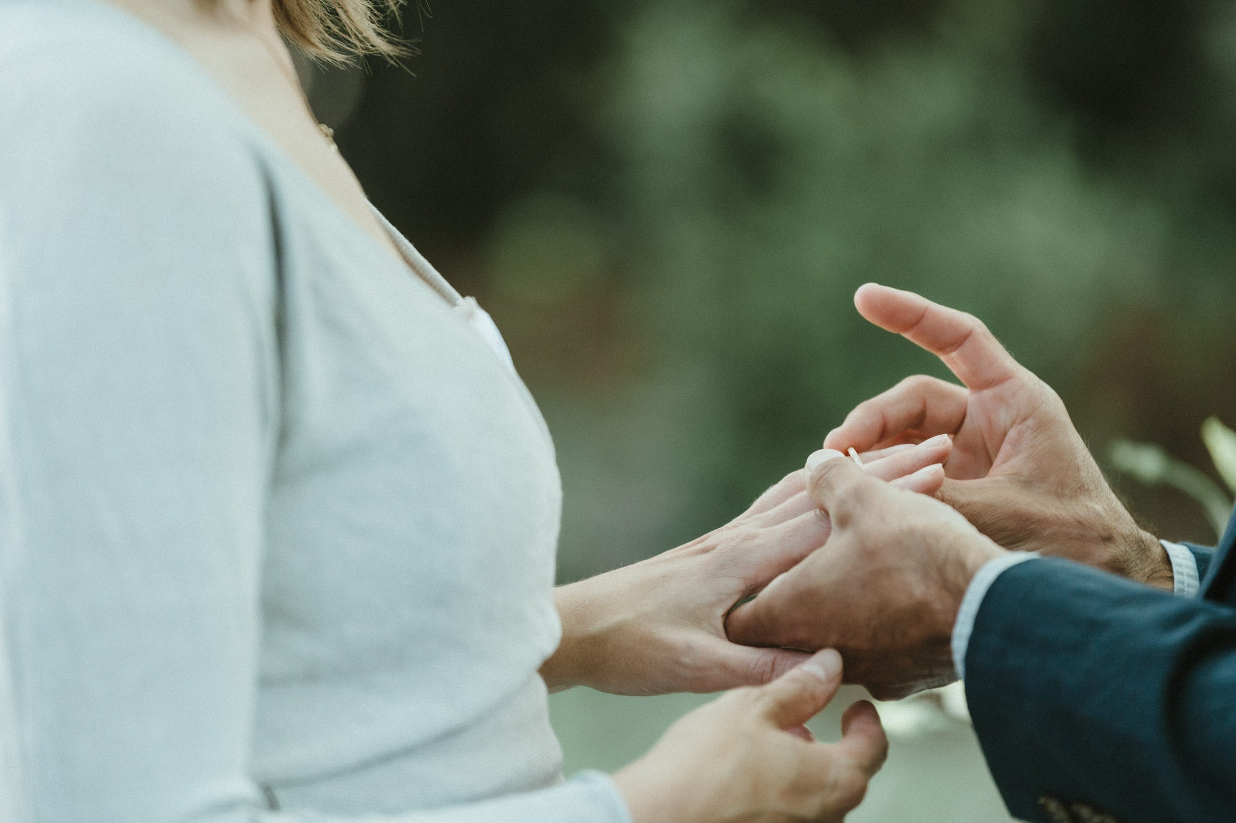 close up groom putting ring on brides finger