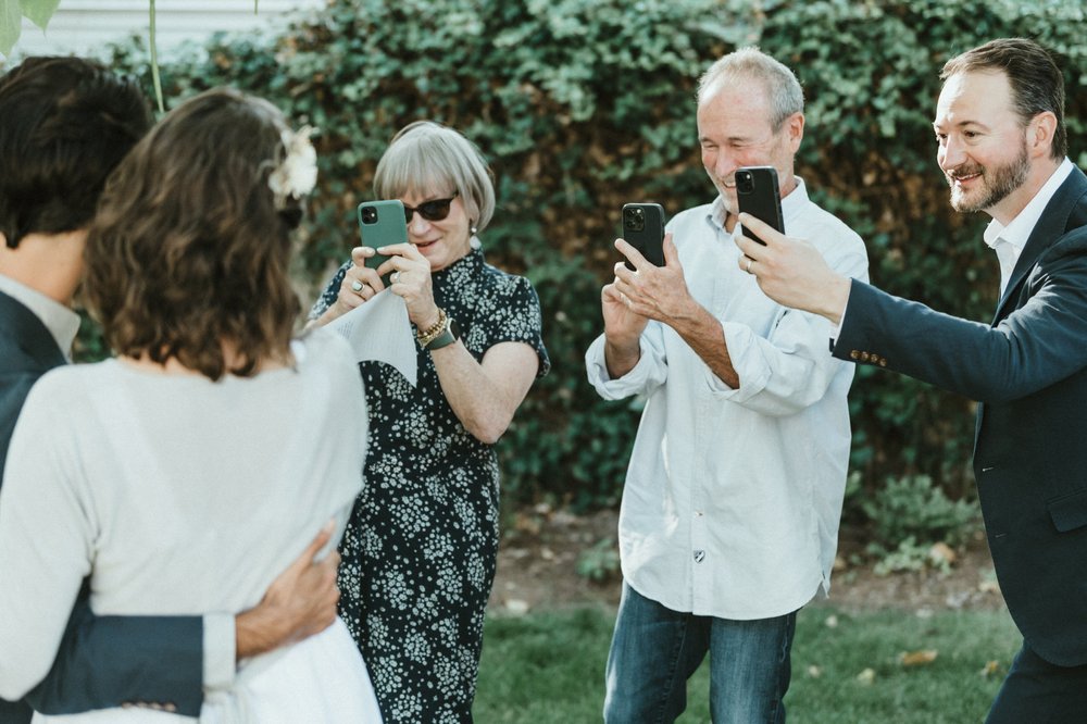 bride and groom guests photographing couple with their phones