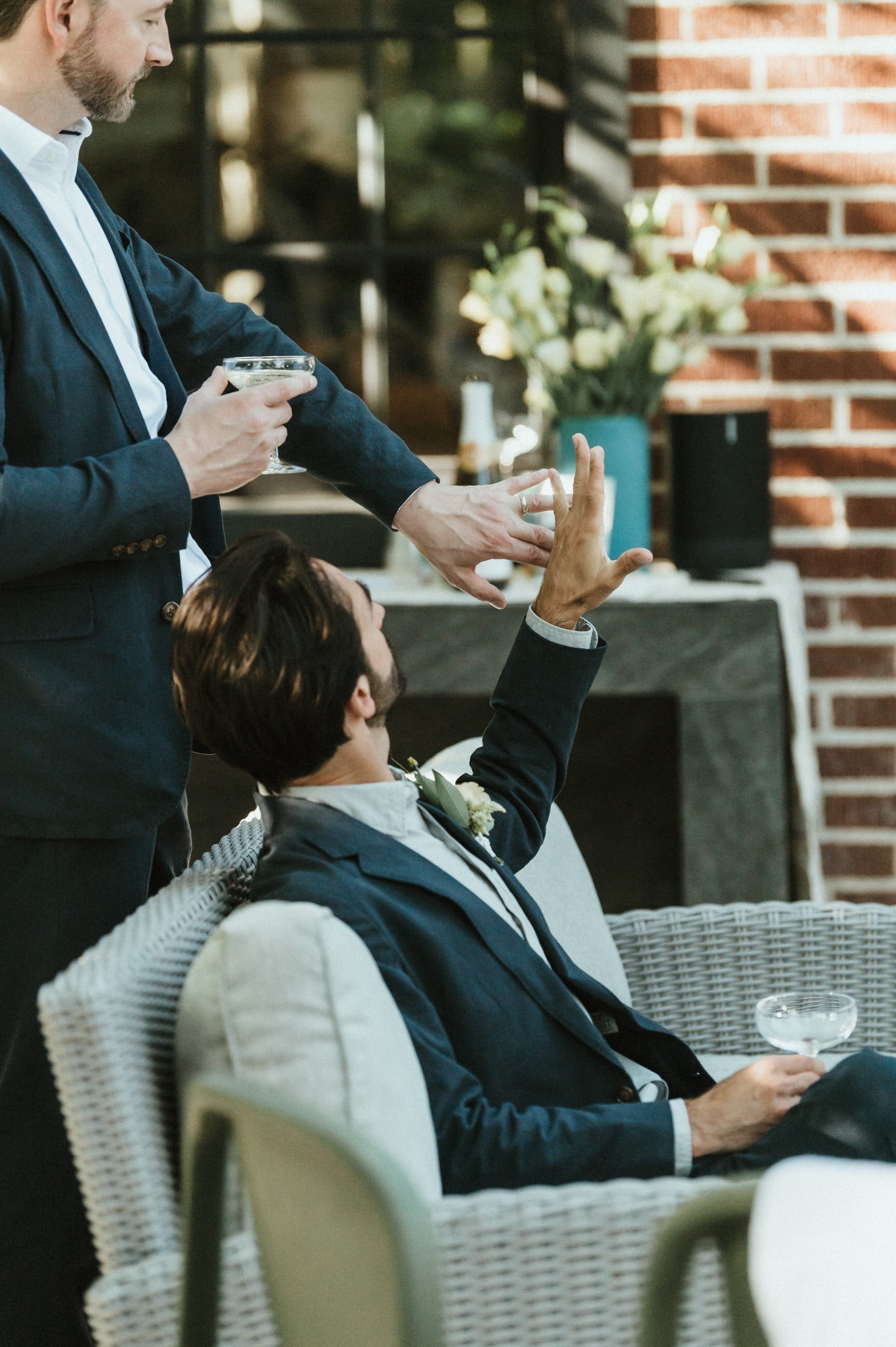 groom and brother showing rings on ring fingers to each other